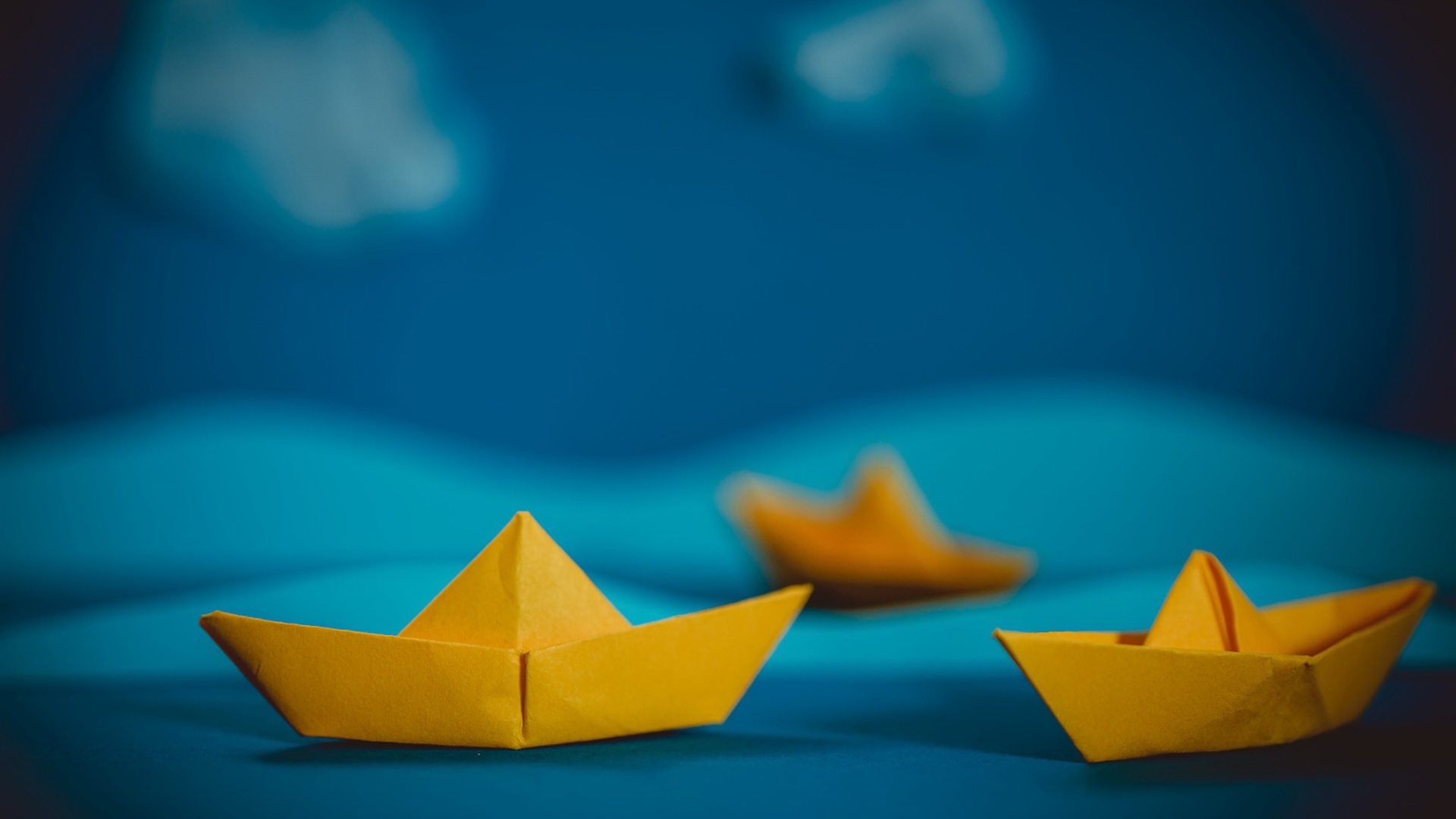 Желтые кораблики оригами на синем фоне