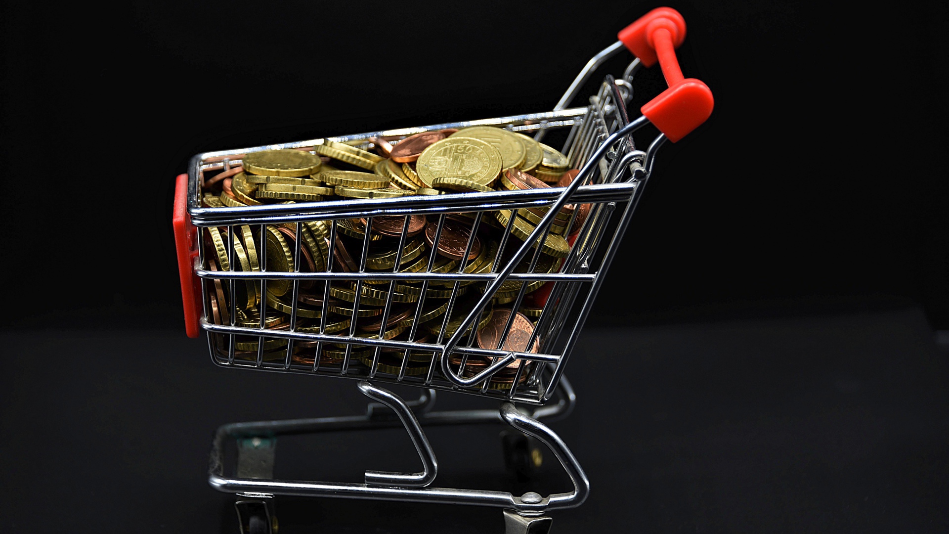Железная тележка с монетами на черном фоне 