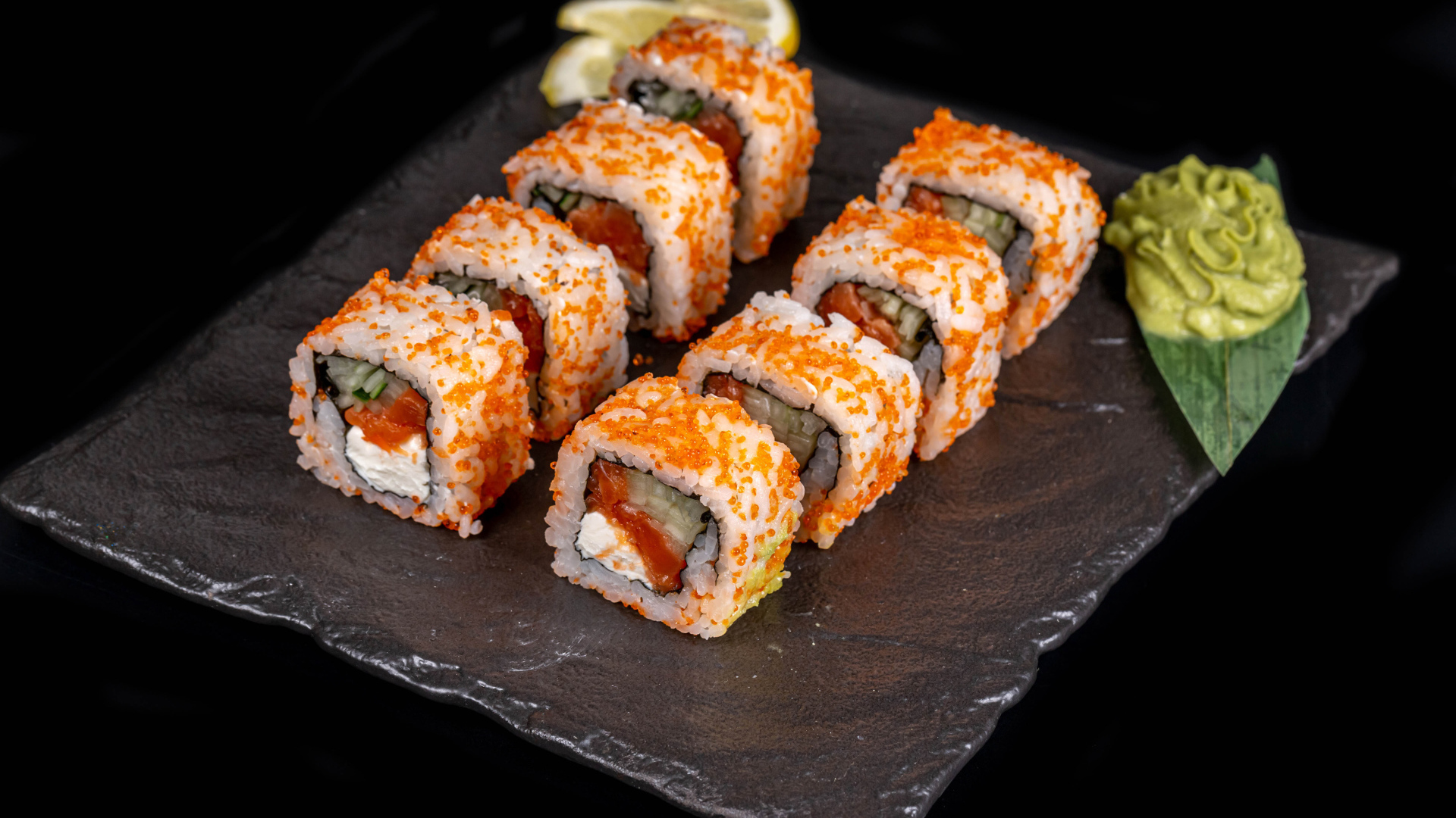 Аппетитные японские роллы с соусом васаби на черном фоне