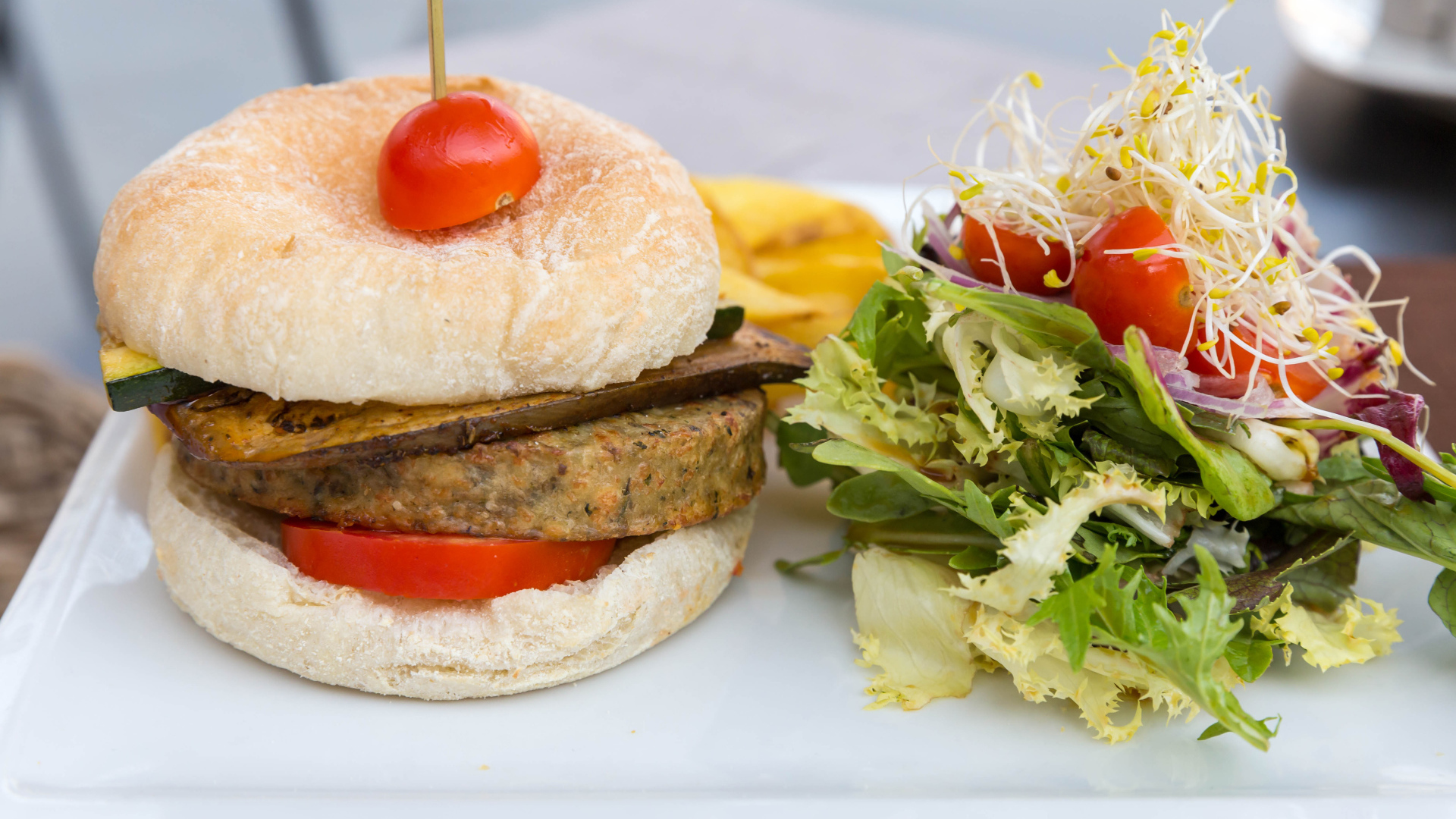 Большой гамбургер с салатом на столе 