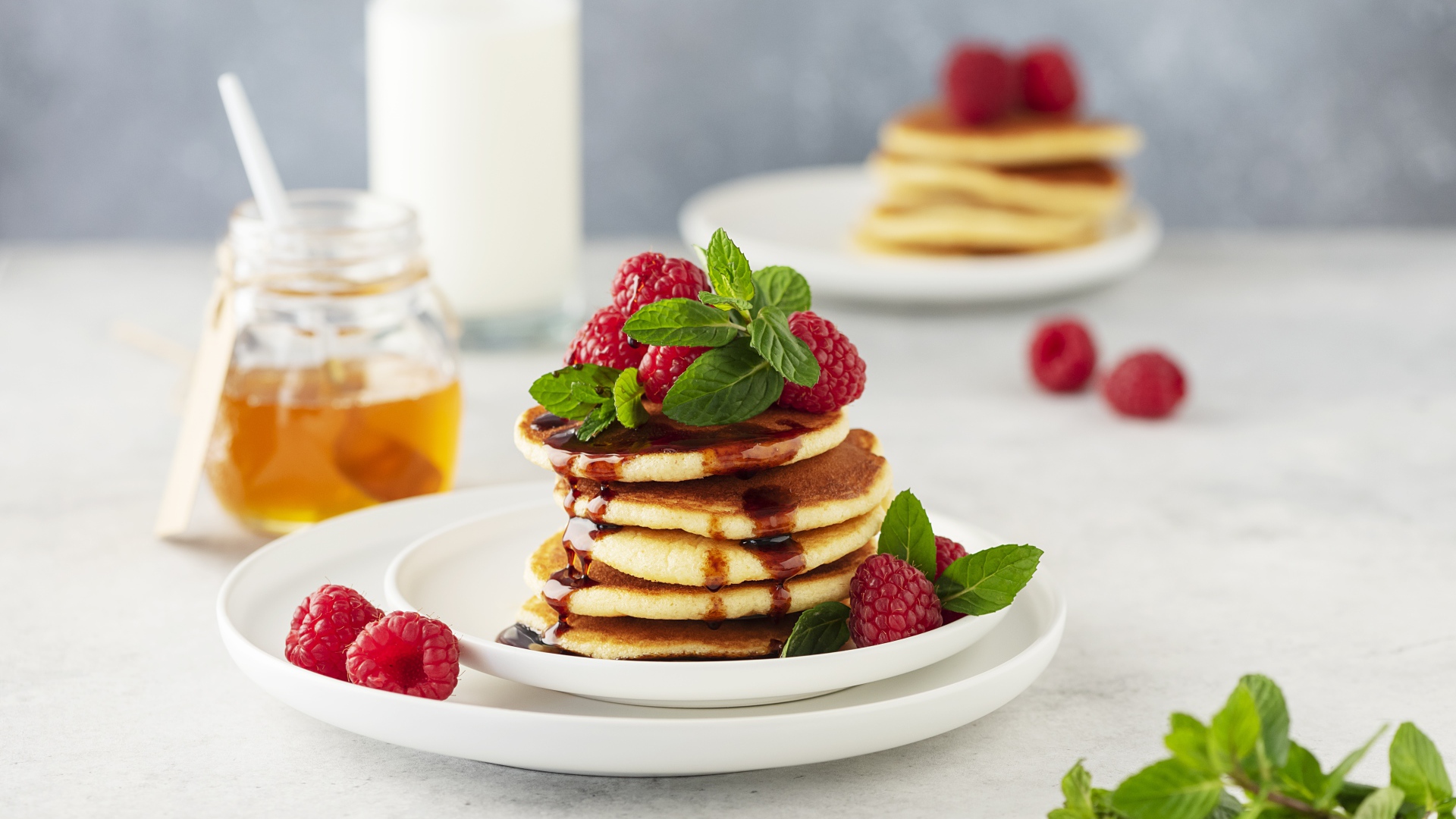 Румяные оладьи на тарелке с малиной и мятой 