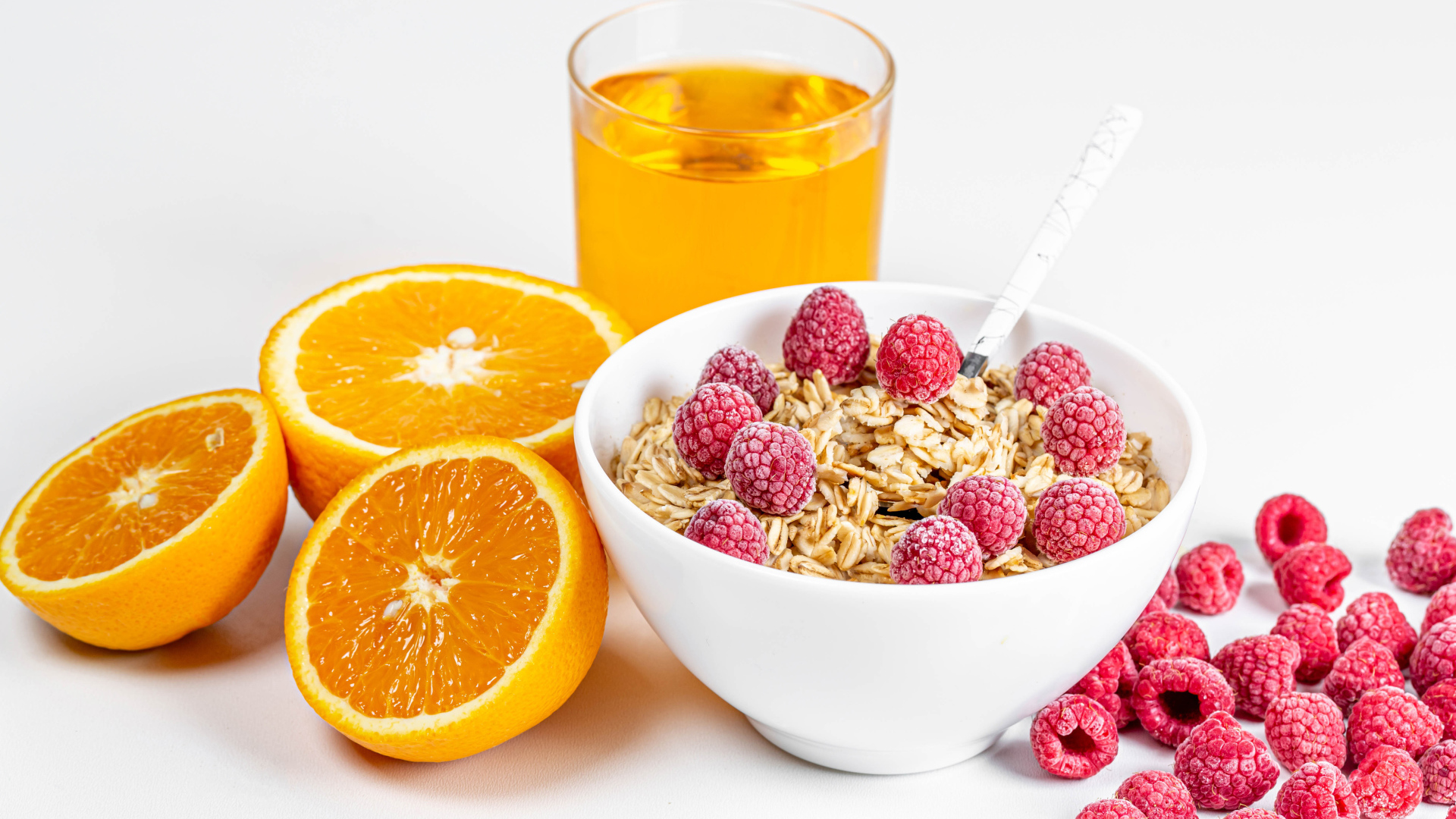 Миска мюсли с ягодами малины и апельсинами на столе с соком