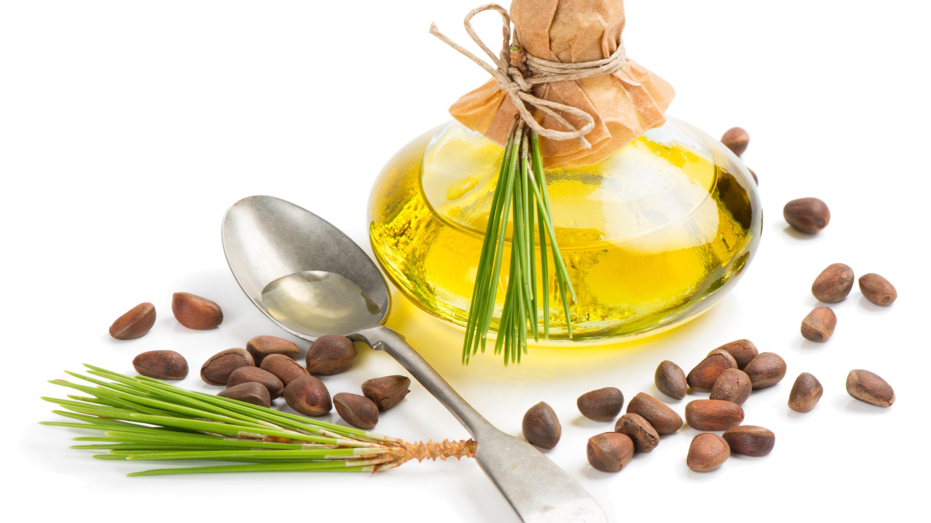 Кедровое масло на белом фоне с орехами и ложкой