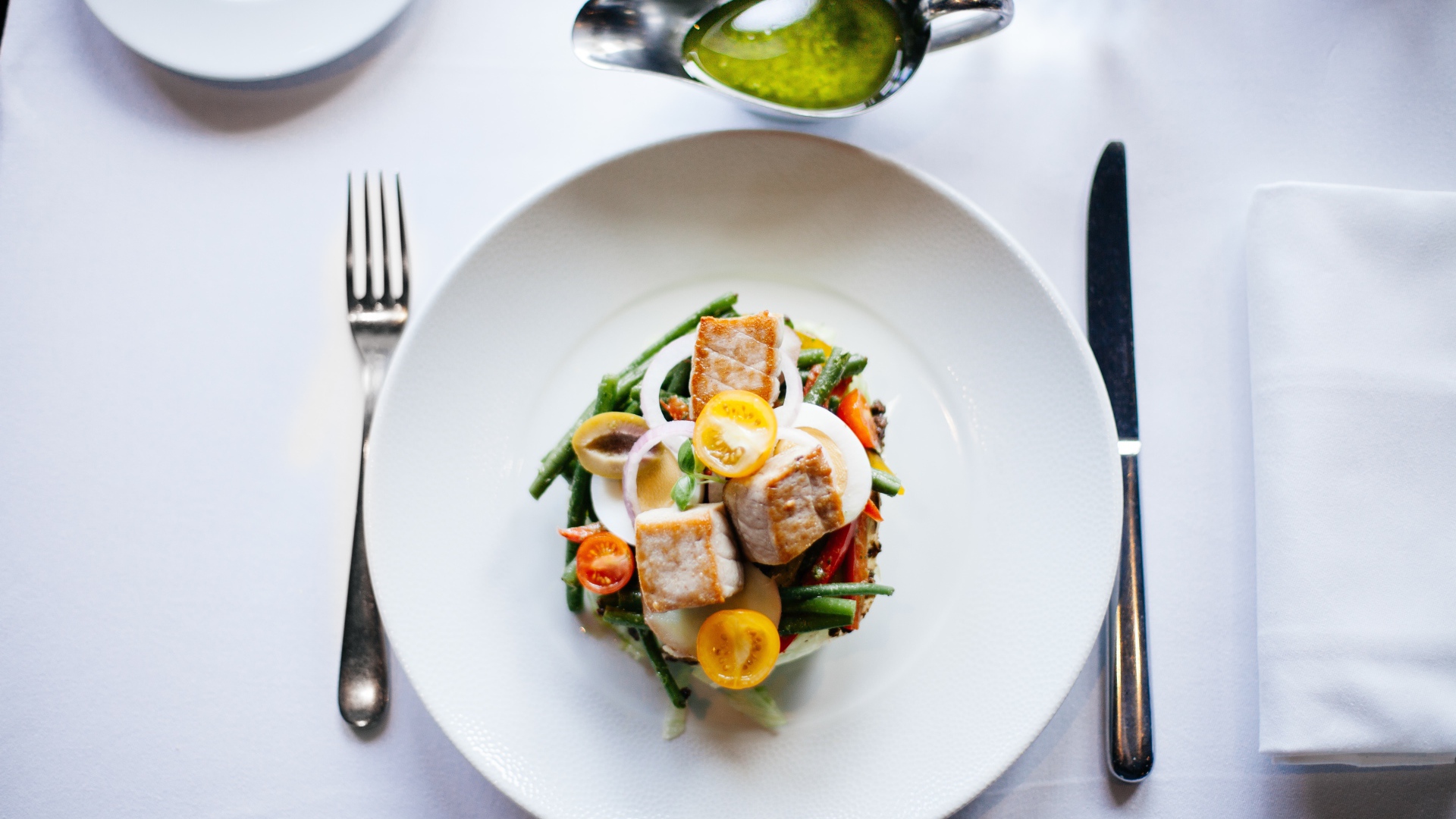 Салат из куриного филе с овощами на белой тарелке