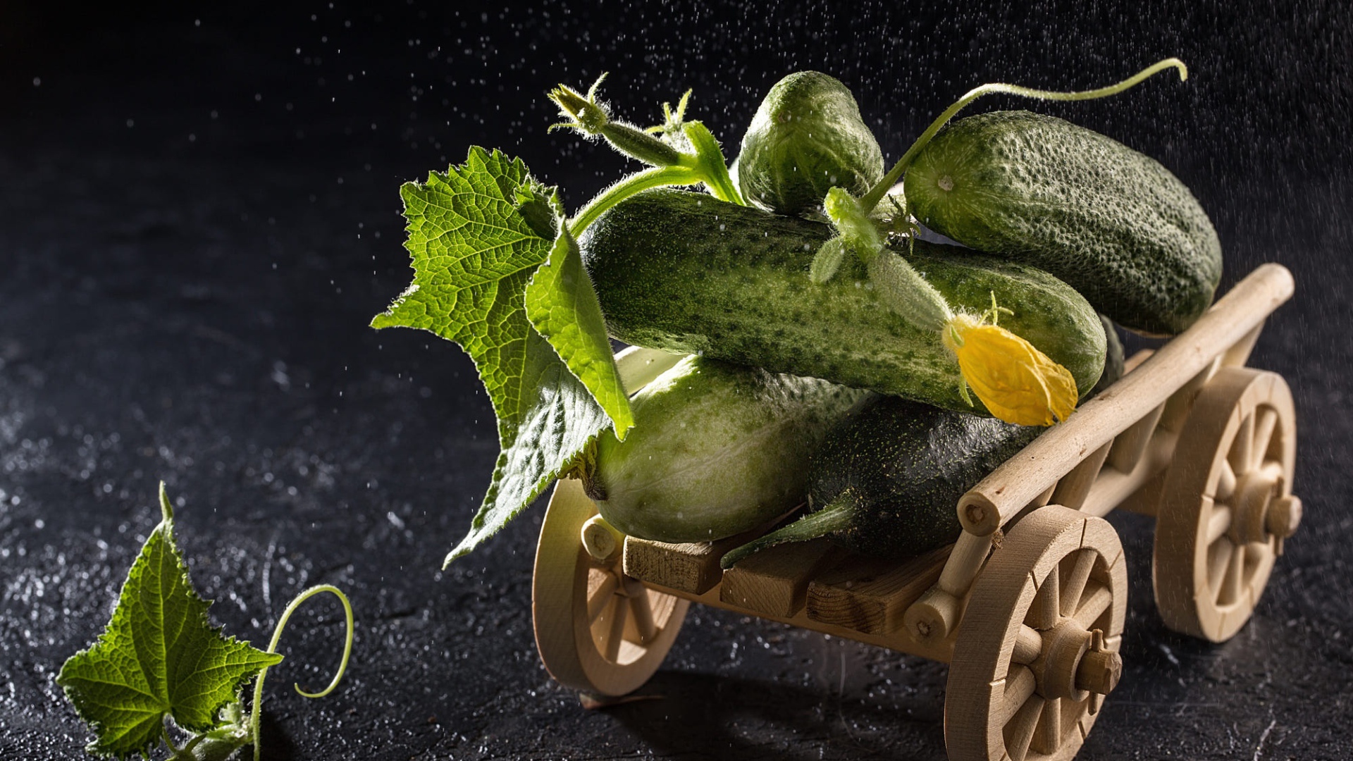 Огурцы на игрушечной тележке на черном столе