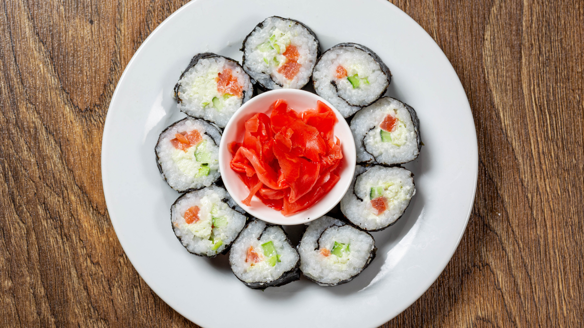 Вкусные суши на большой белой тарелке с имбирем