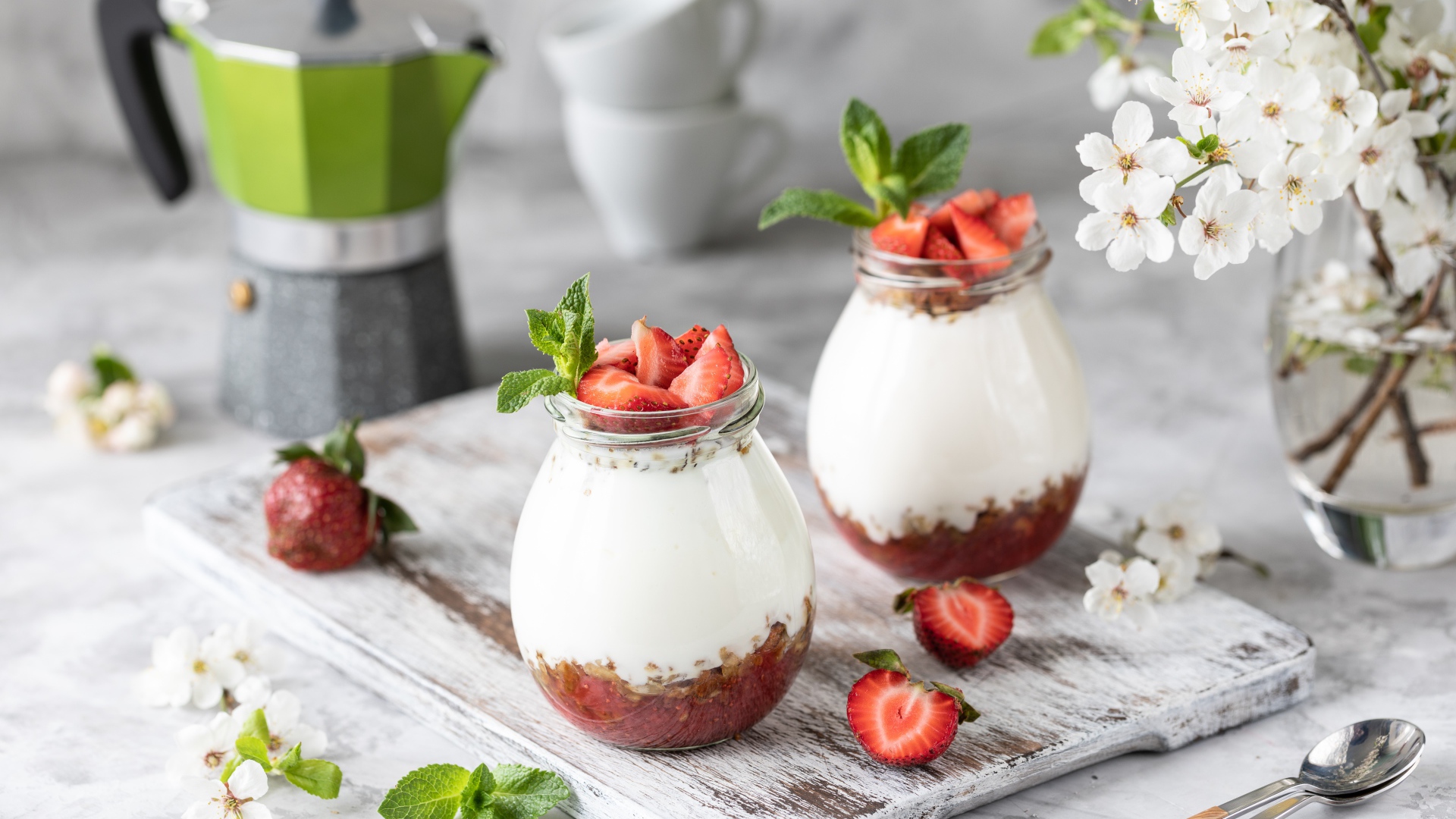 Десерт с йогуртом в банке с клубникой на столе цветами вишни 