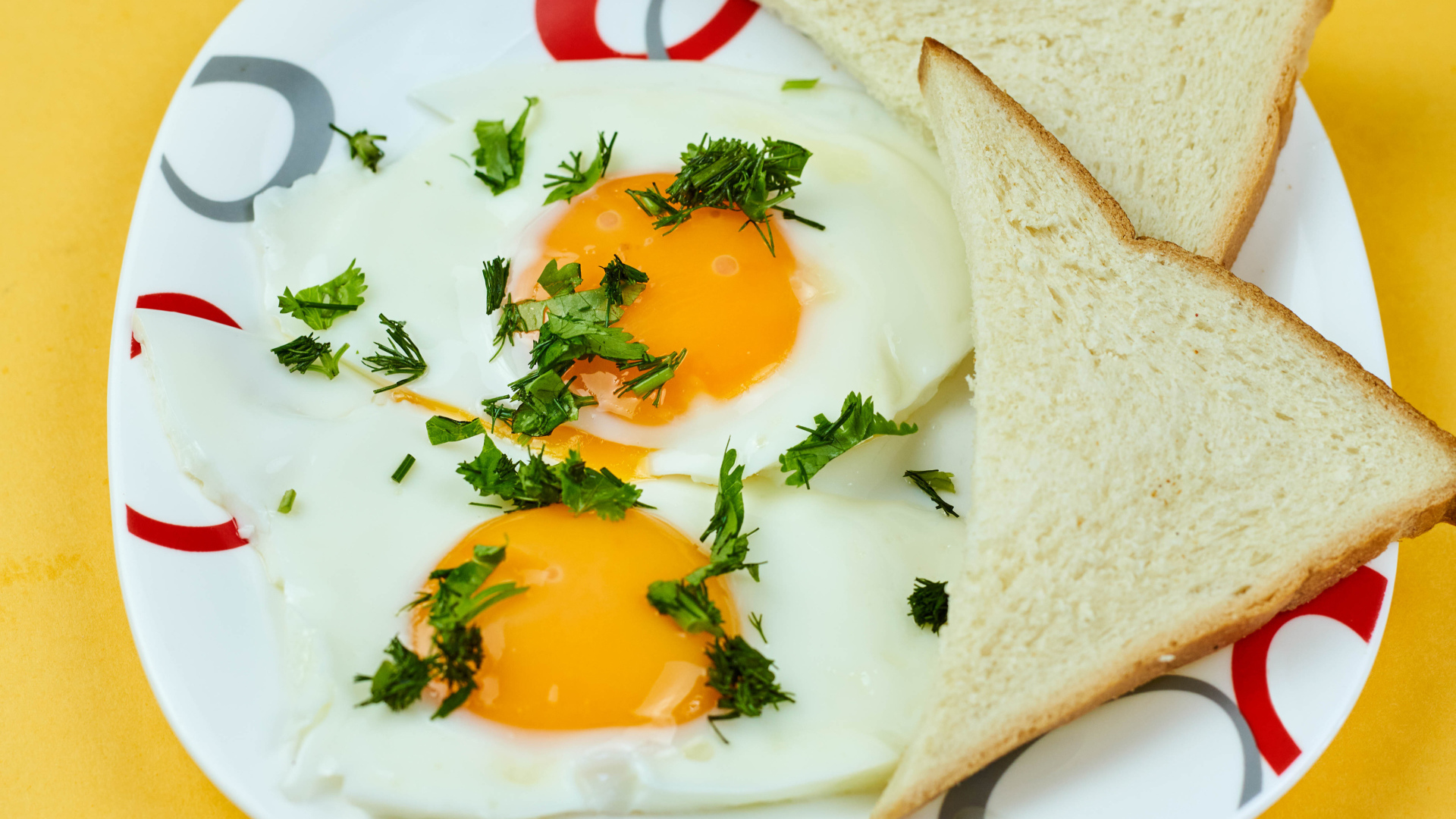 Яичница глазунья с зеленью на тарелке с хлебом 