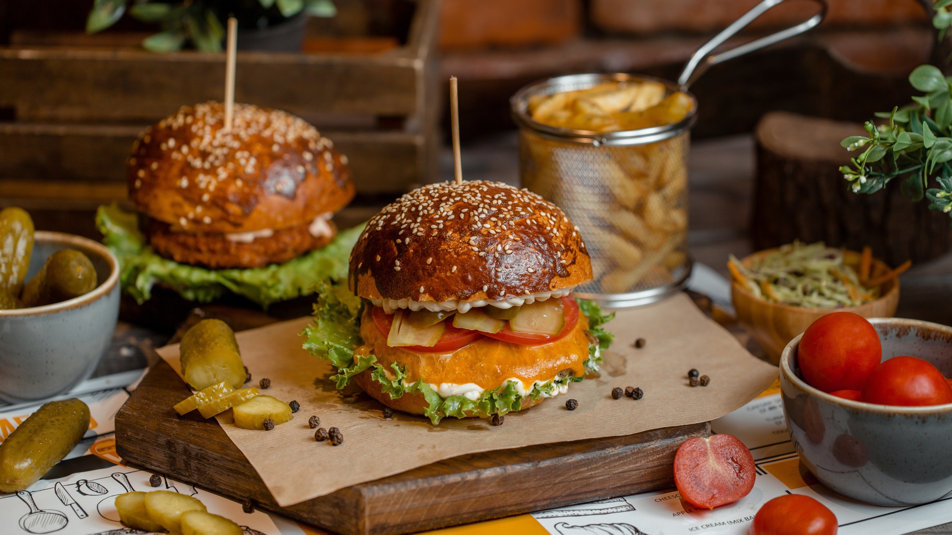 Hamburgers on the table with tomatoes, french fries and pickles
