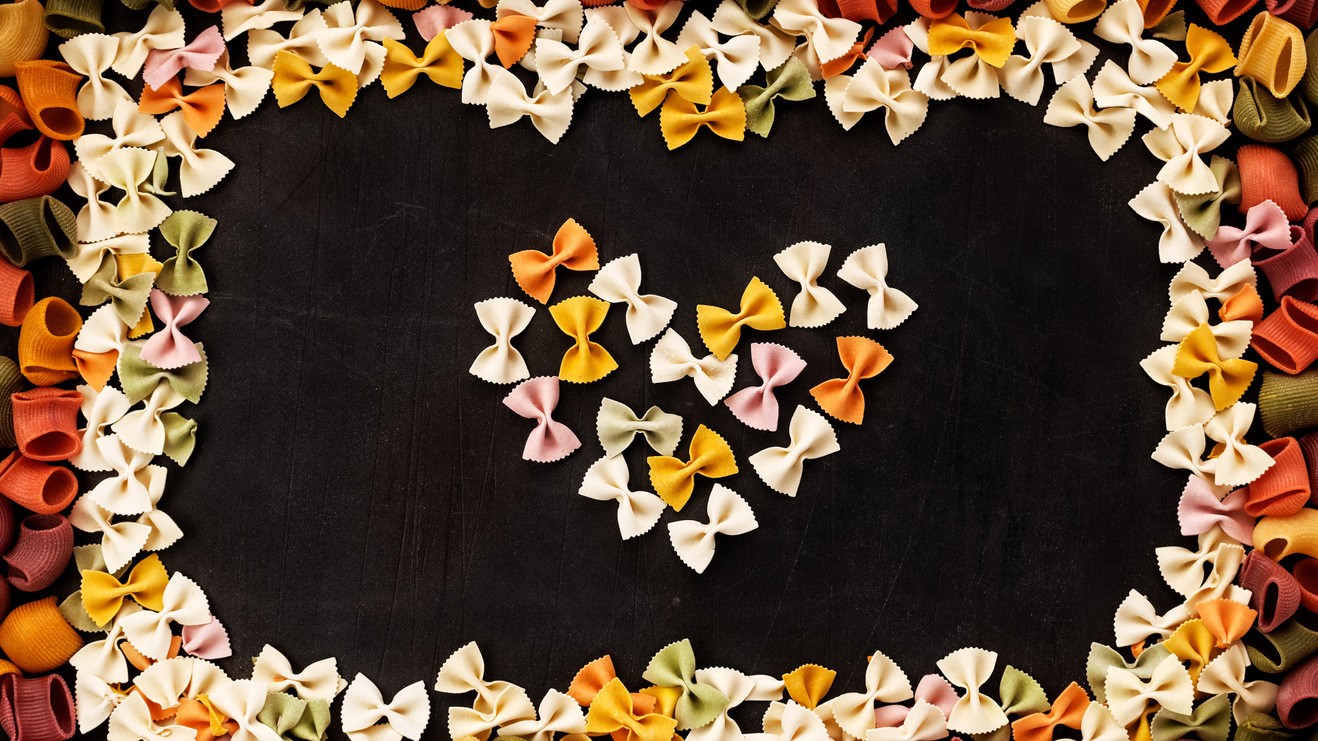 Сердце из разноцветных макарон на черном столе 