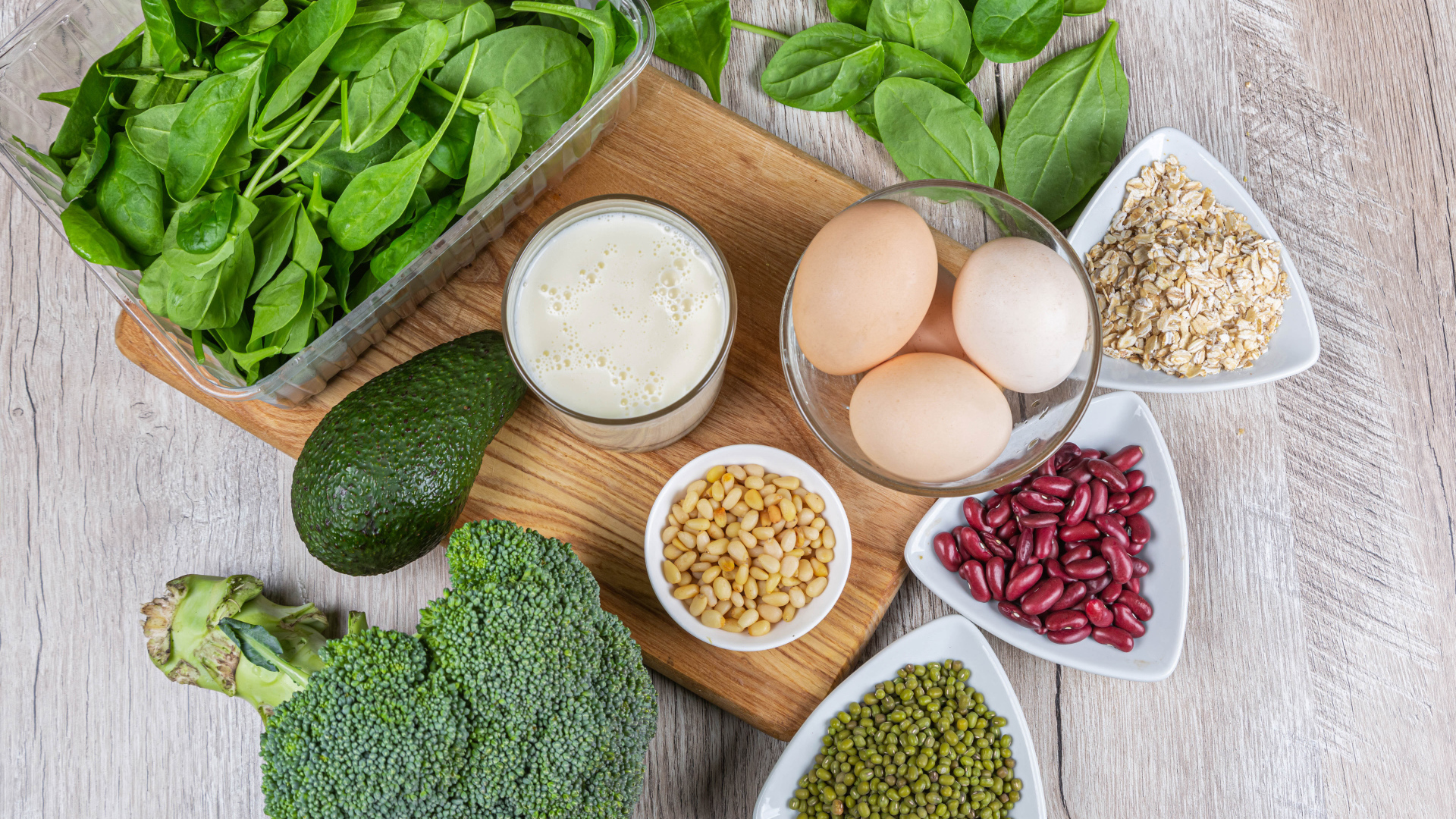 Бобовые, авокадо, базилик, яйца молоко и брокколи на столе