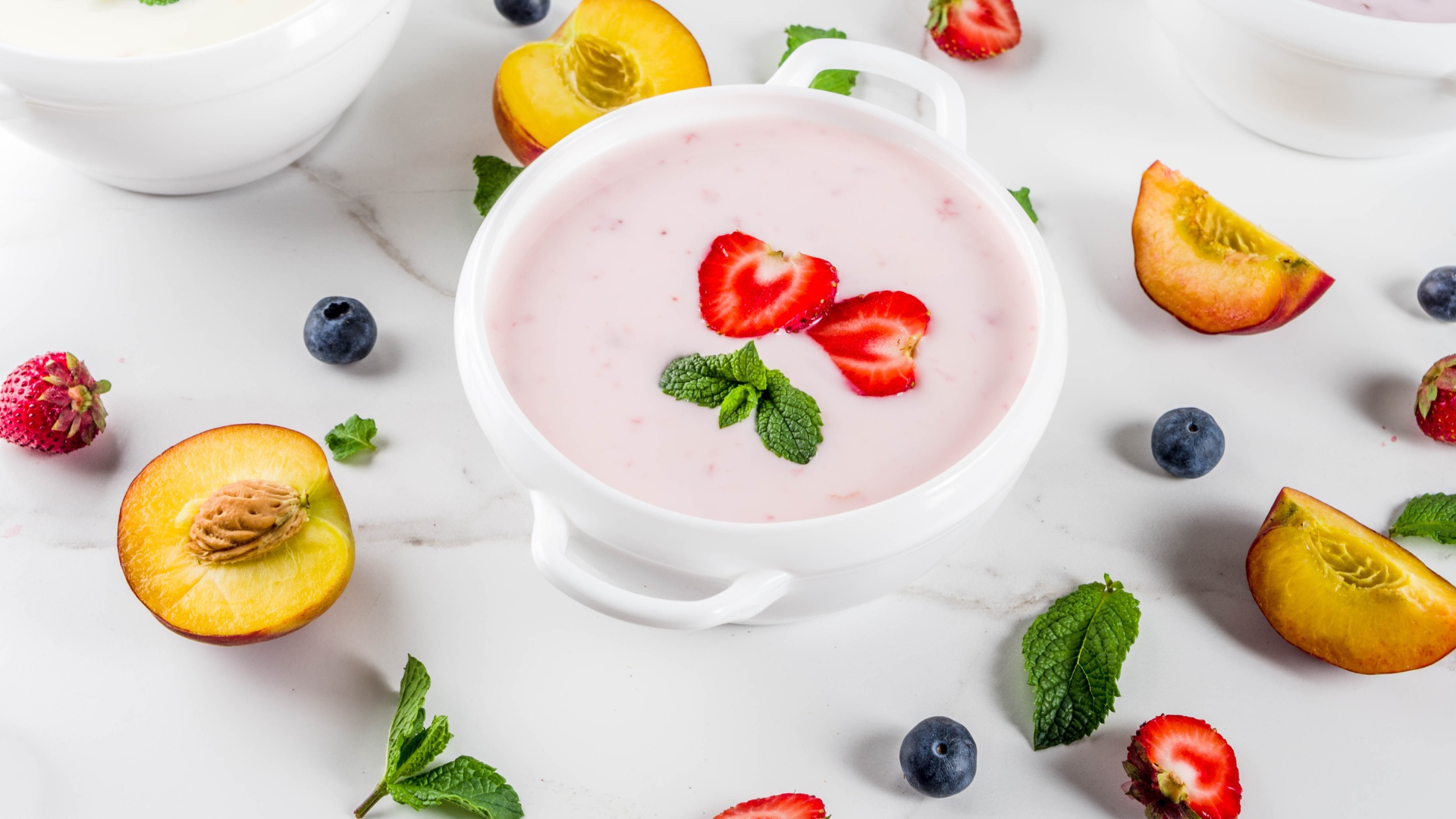 Молочный суп в тарелке на столе с ягодами и нектарином