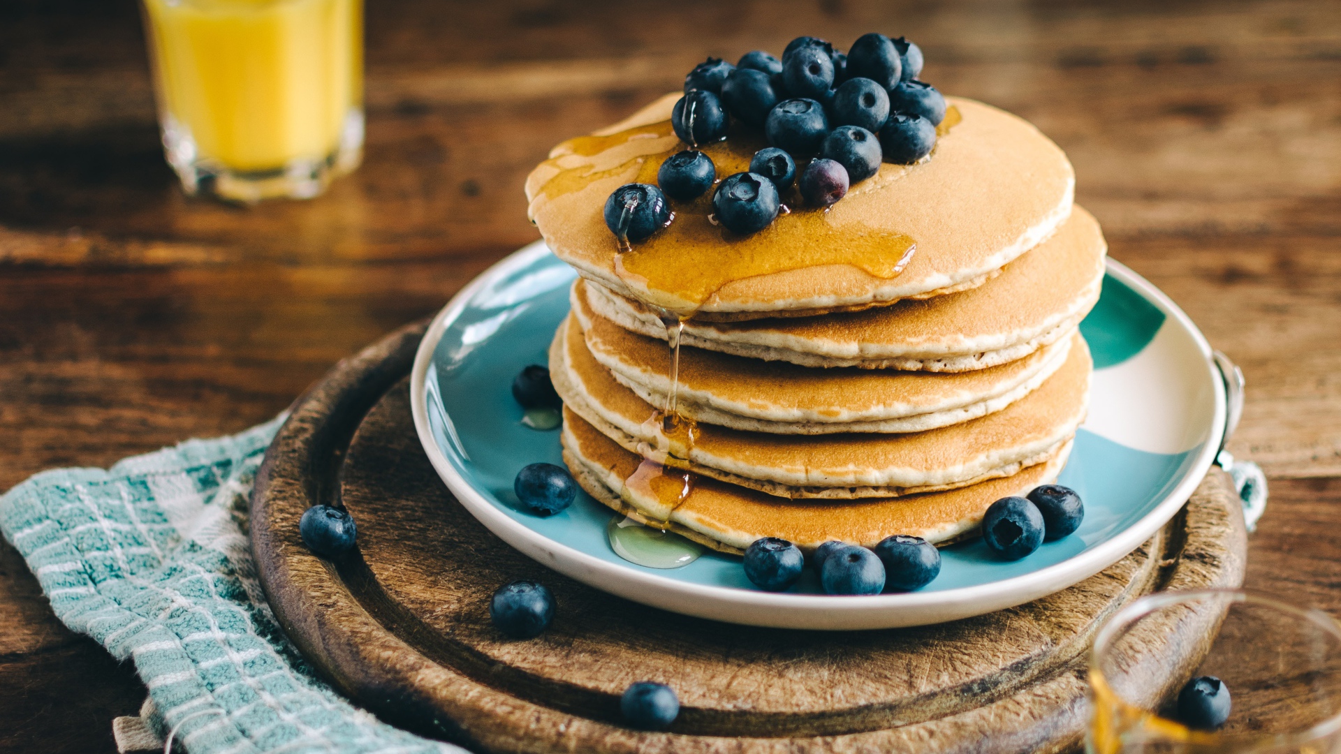 Румяные оладья на тарелке  с медом и ягодами черники 