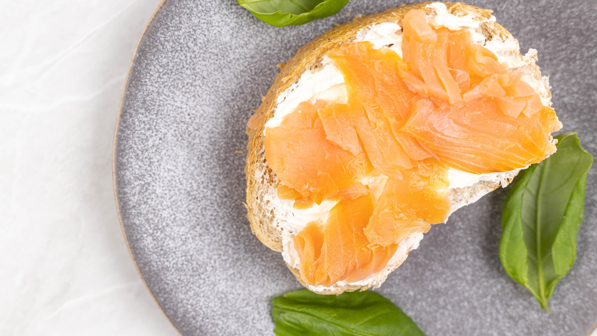 Бутерброд с сыром, красной рыбой и листьями базилика