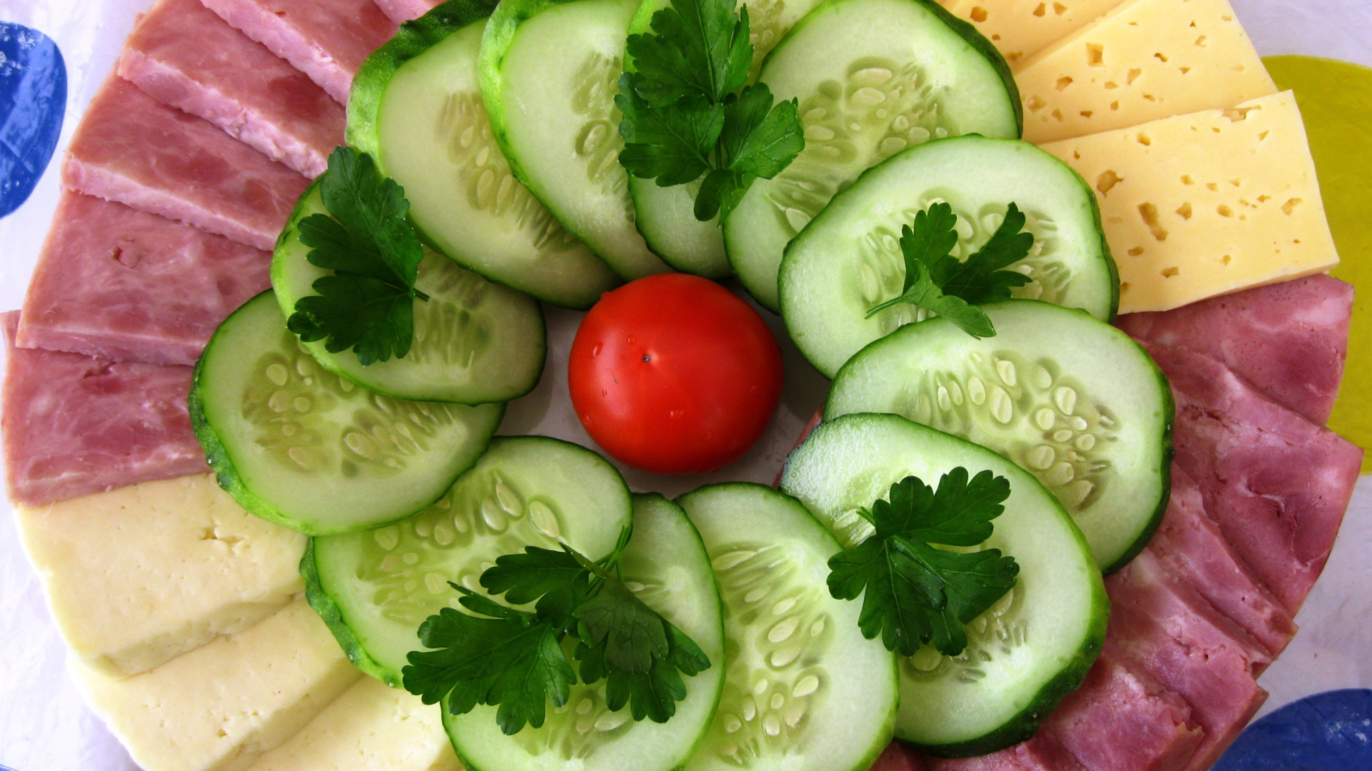 Сыр нарезанный, огурцы и ветчина на тарелке 