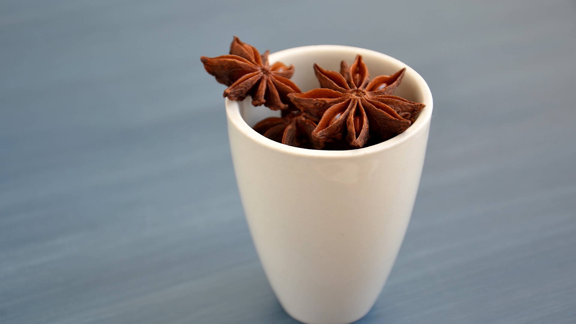 Звездочки бадьяна в белой чашке на столе 