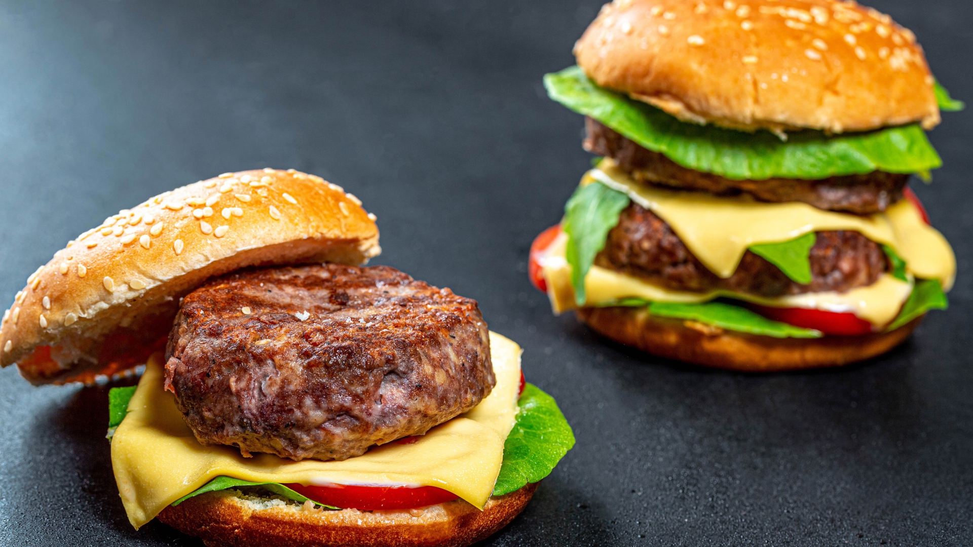 Два аппетитных гамбургера с сочной котлетой на сером фоне