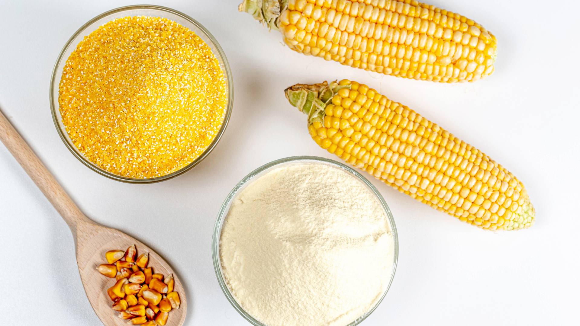 Два початка кукурузы на белом фоне с крупой и мукой 