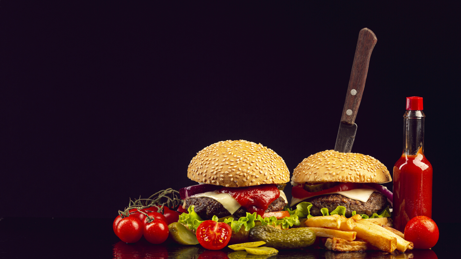 Два гамбургера на столе с ножом, овощами и кетчупом 