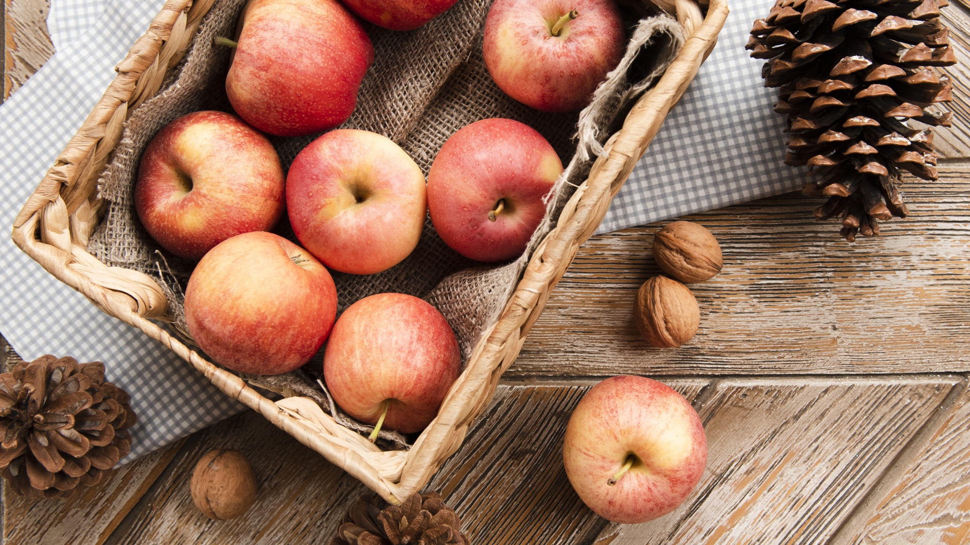 Корзина с яблоками на столе с сосновыми шишками