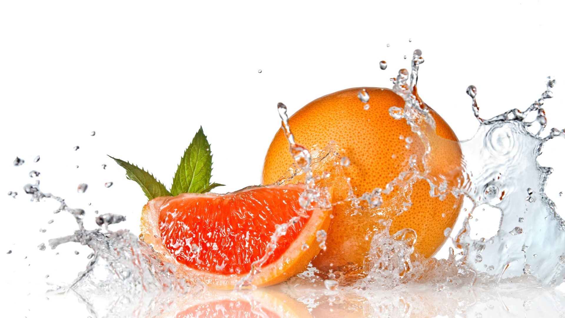 Большой спелый апельсин в брызгах воды на белом фоне
