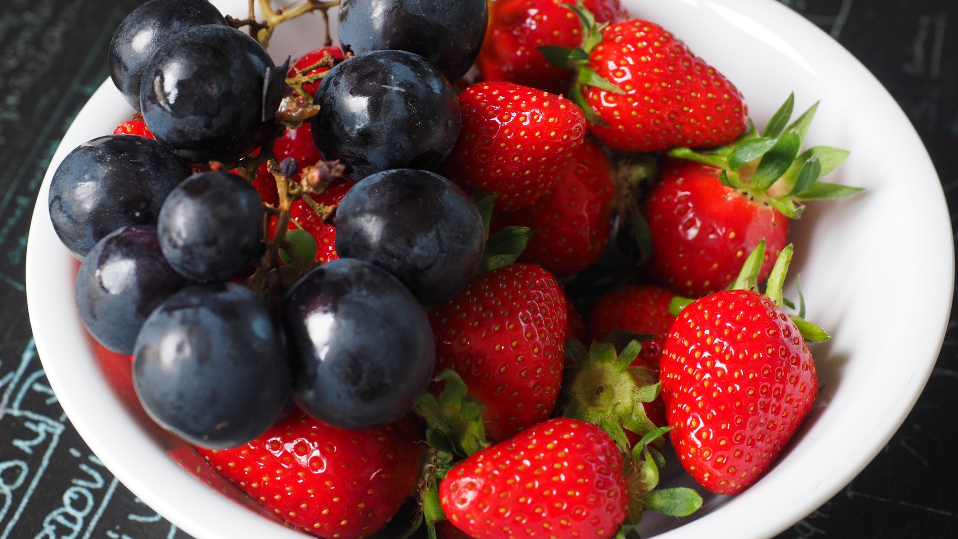 Синий виноград на тарелке с ягодами клубники 