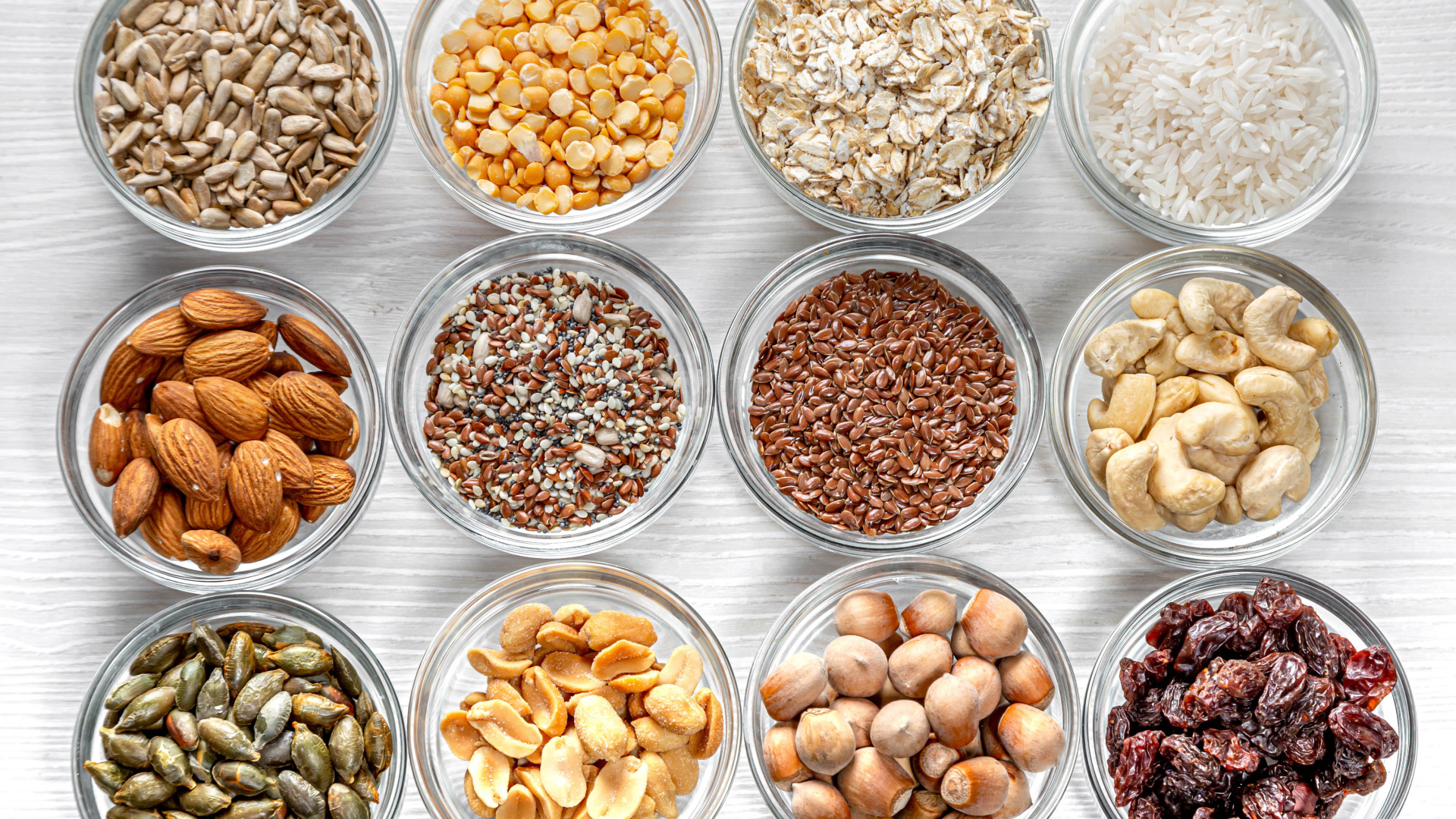 Разные виды орехов, круп и зерен в тарелках вид сверху 