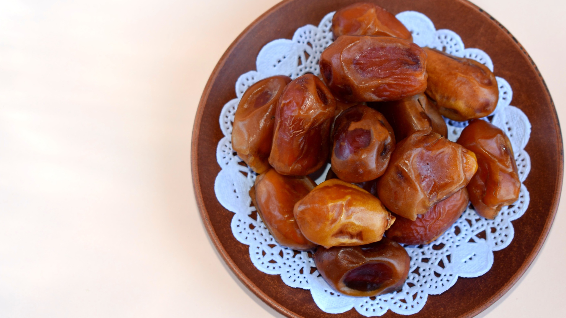 Сушеные финики в деревянной миске на белом фоне