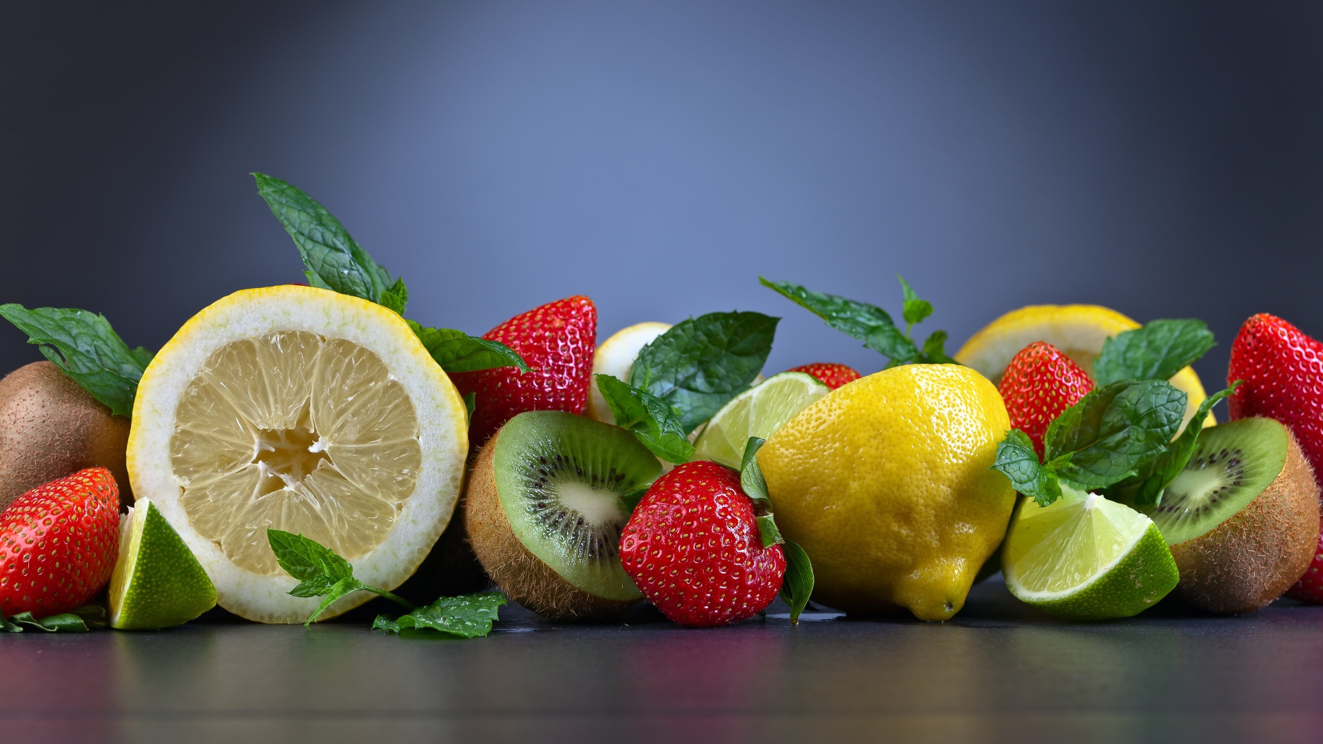 Лимоны на столе с киви и ягодами клубники 