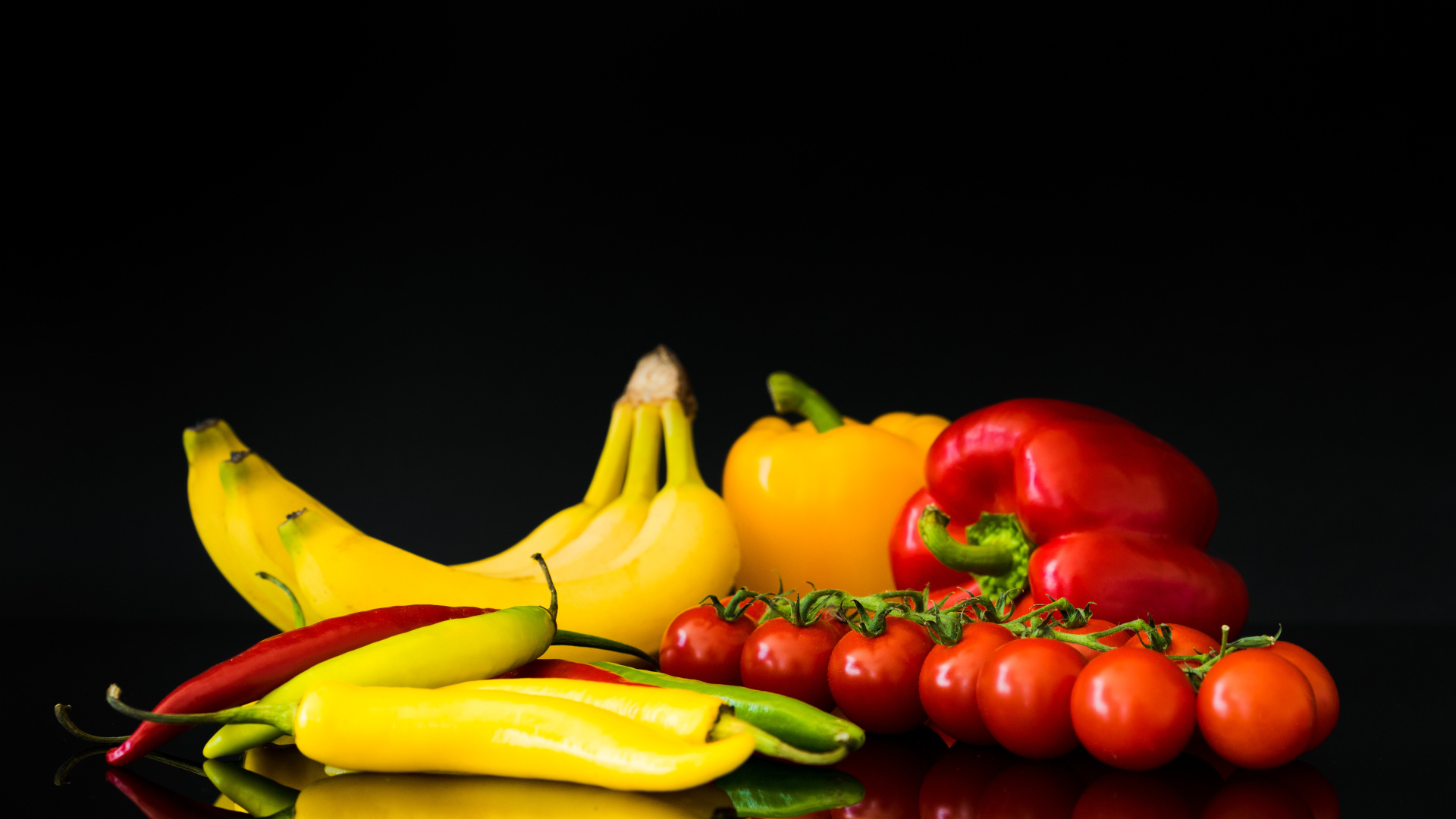 Перец, помидоры и бананы на черном фоне