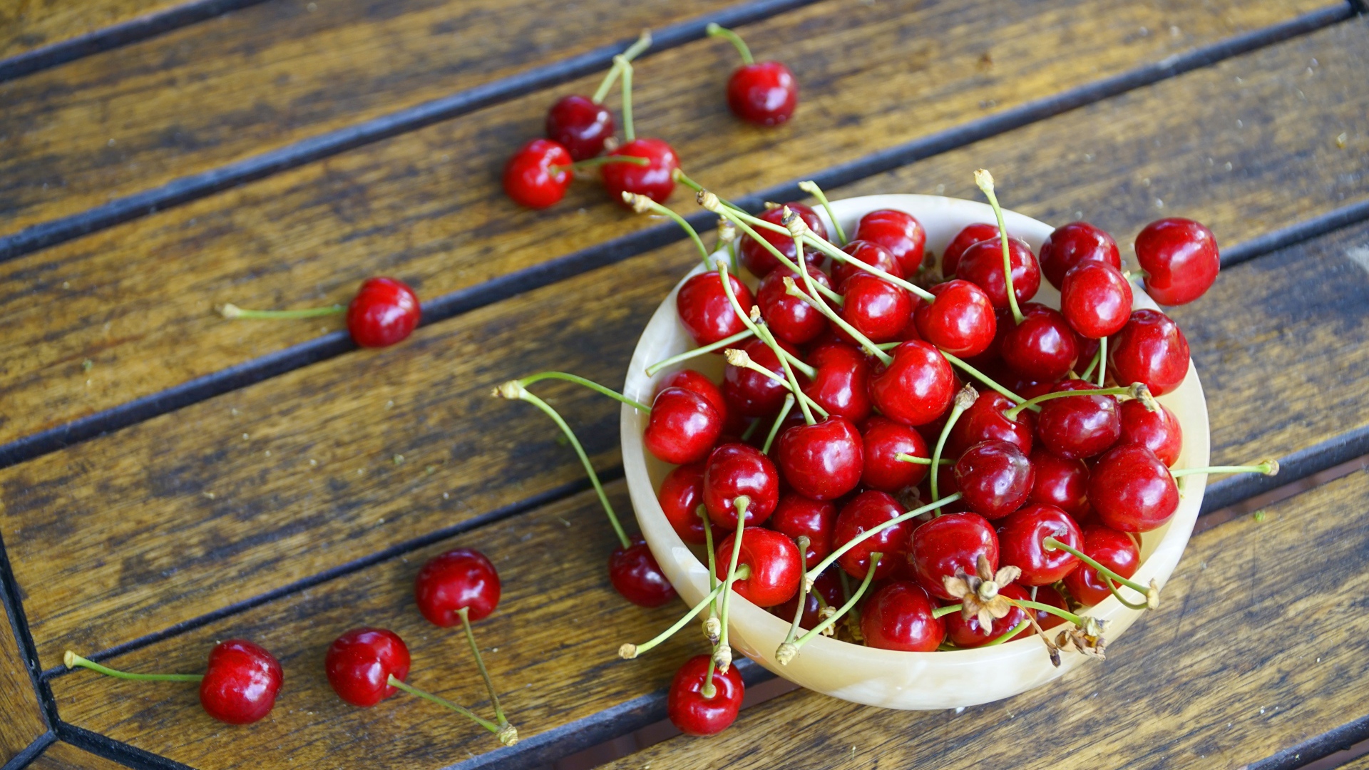 Спелые красные вишни в тарелке на столе 