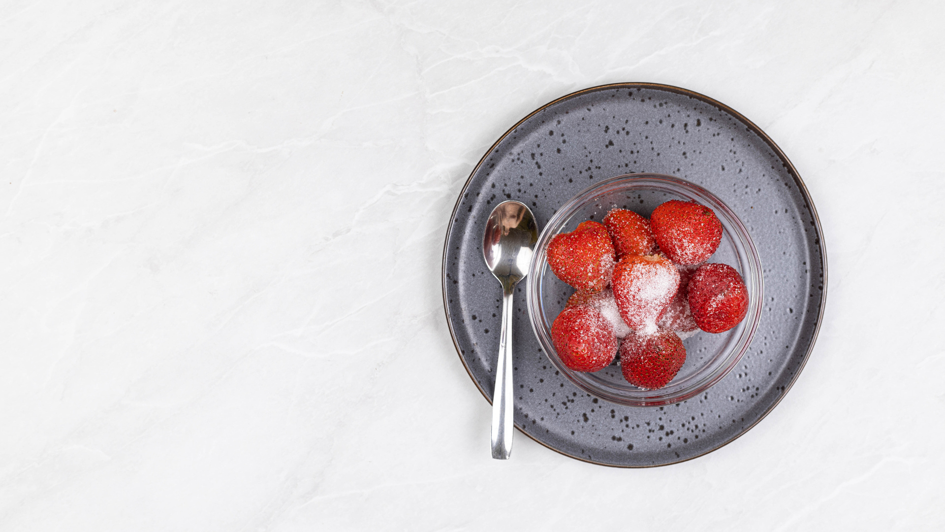 Спелая красная клубника в миске с сахаром на белом фоне