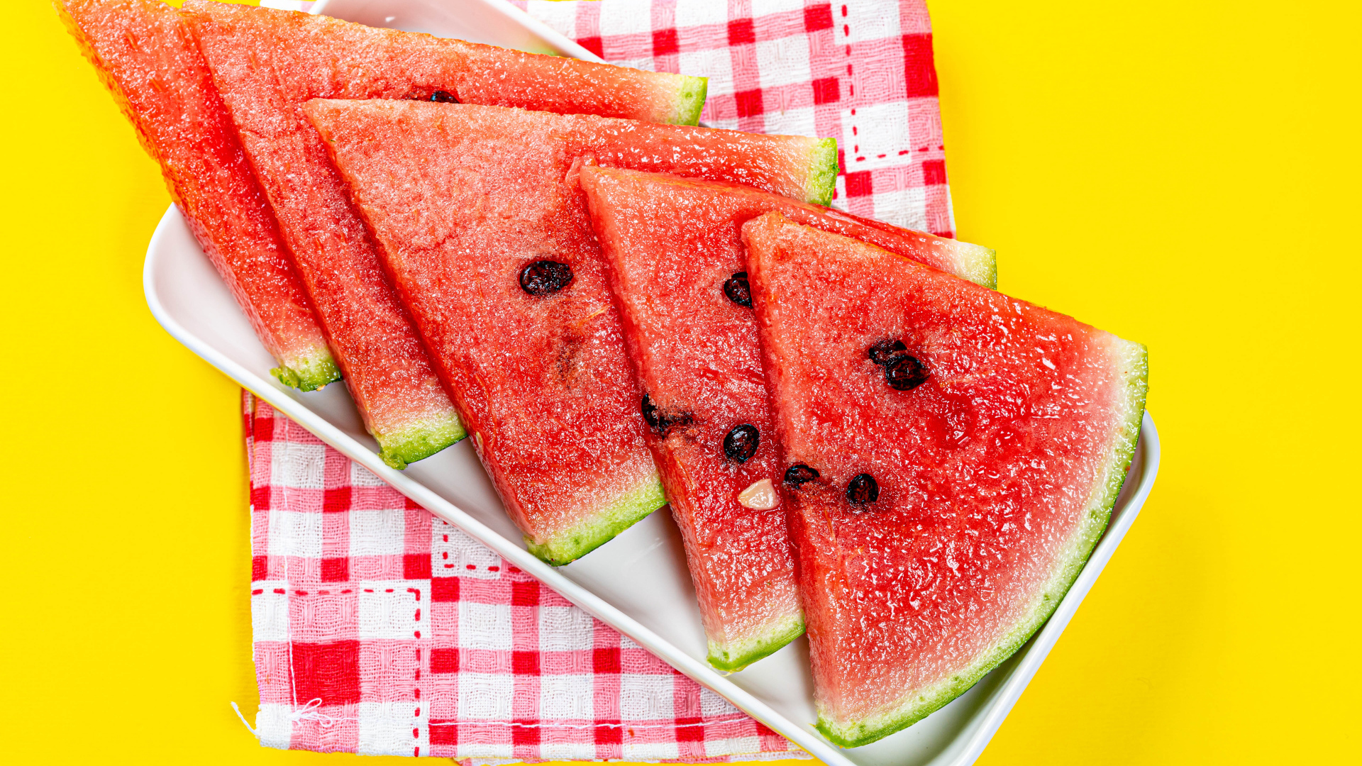 Кусочки сочного арбуза в тарелке на желтом столе