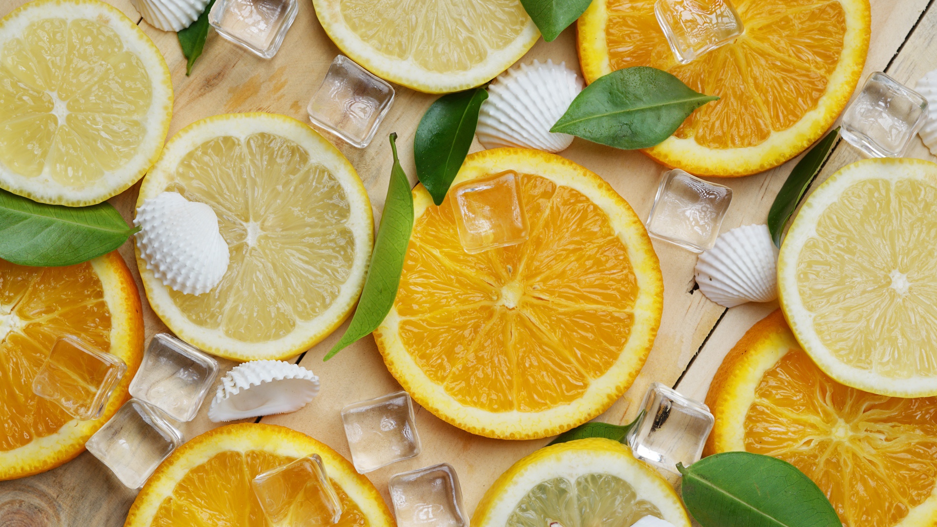 Кусочки апельсина и лимона на столе с кубиками льда и ракушками