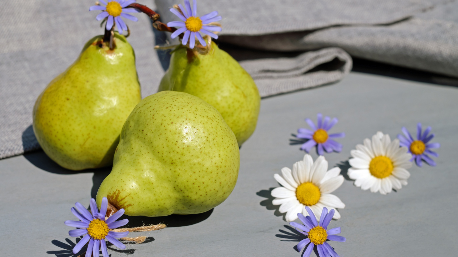Три груши на столе с цветами