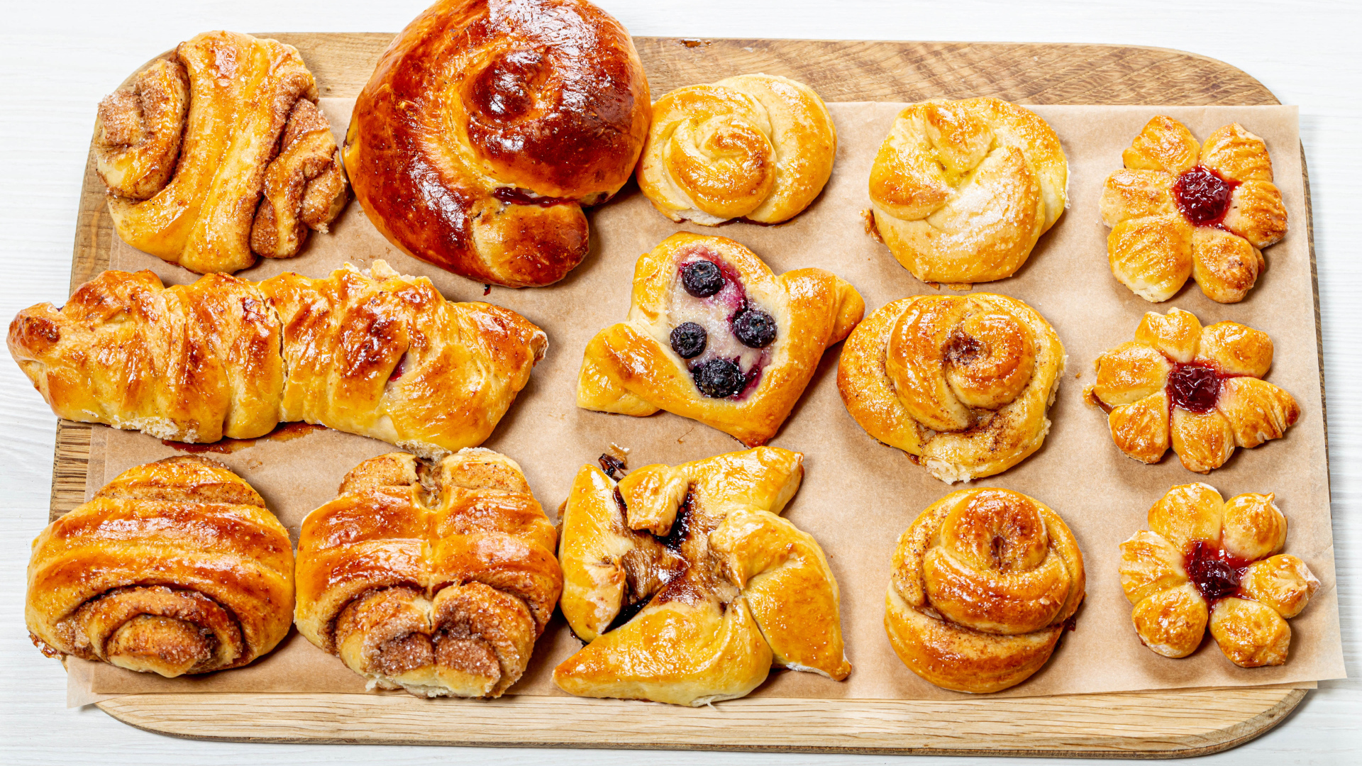 Разная свежая выпечка на доске на белом фоне