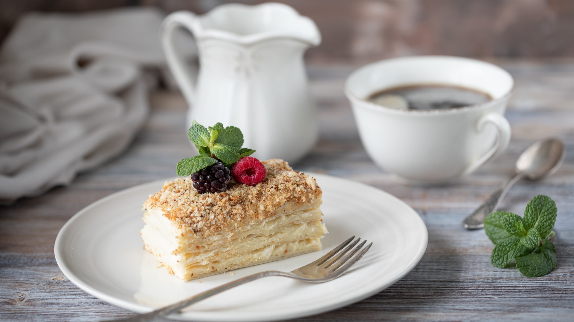 Кусок торта лежит на белой тарелке на столе с кофе