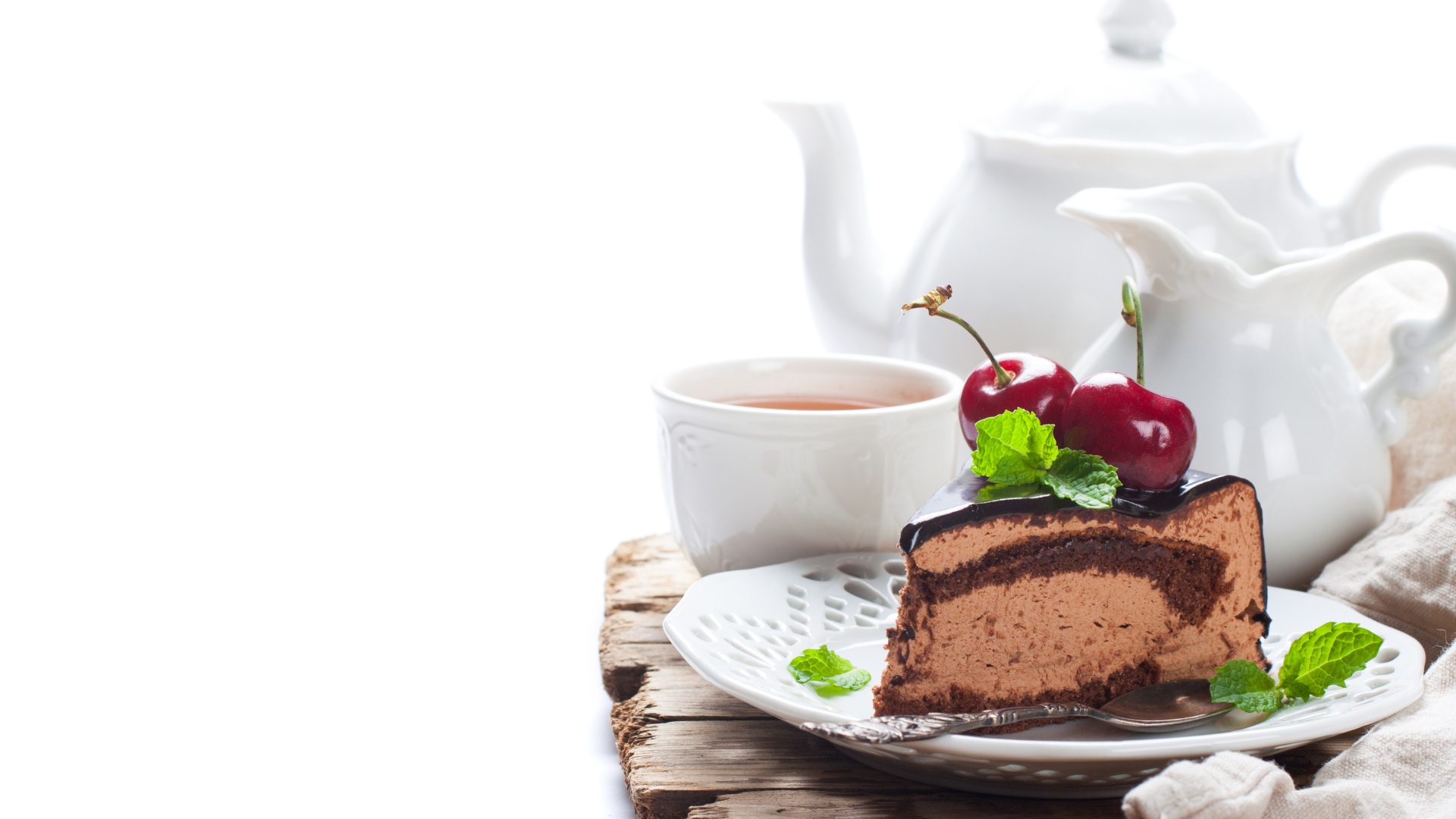 Кусок торта с ягодами черешни на столе с чаем