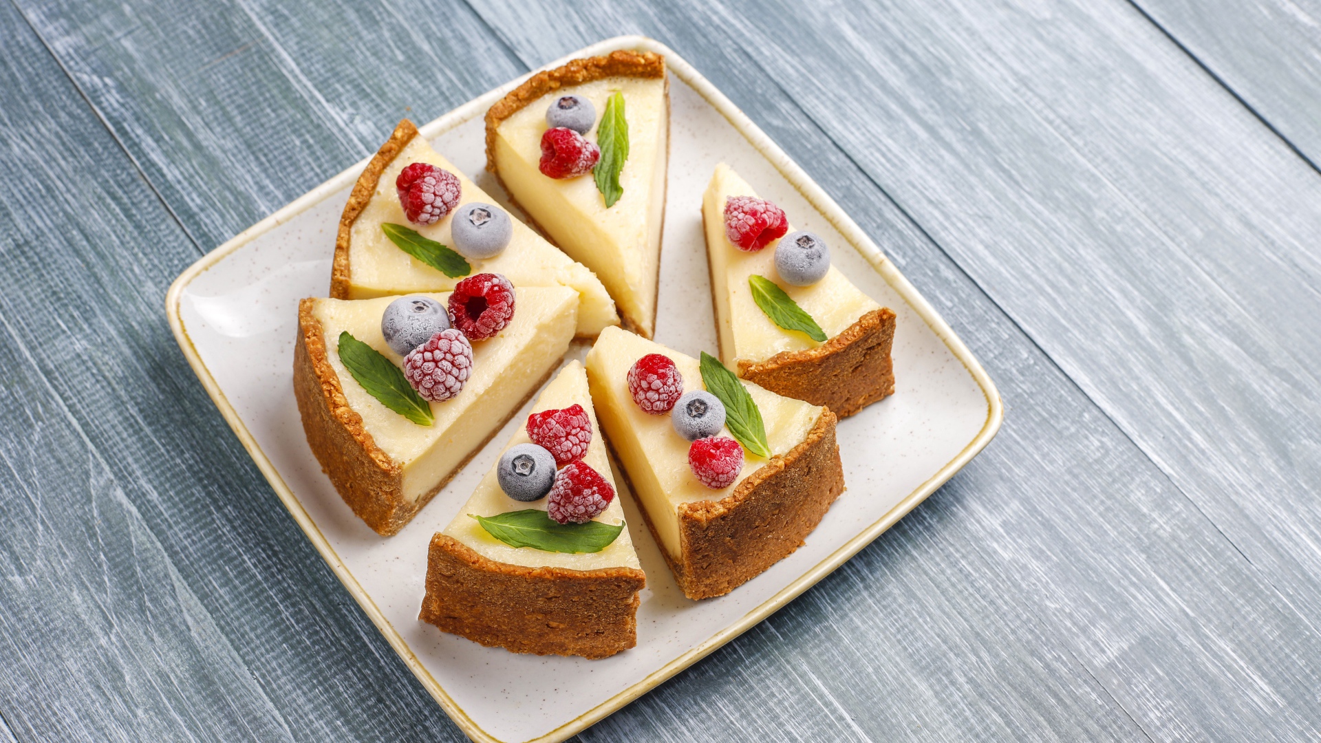 Аппетитный чизкейк с ягодами нарезан кусками на тарелке 