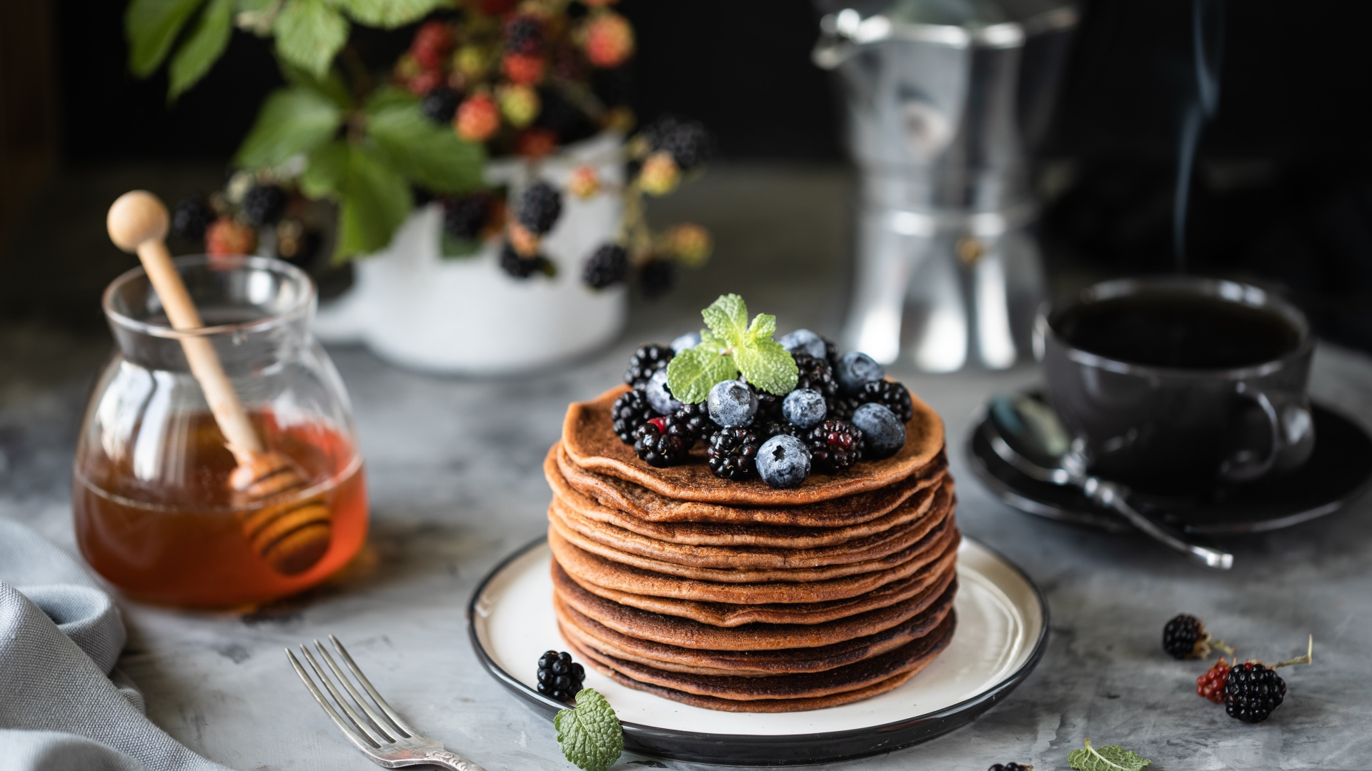 Гречневые блинчики с ягодами на столе с медом