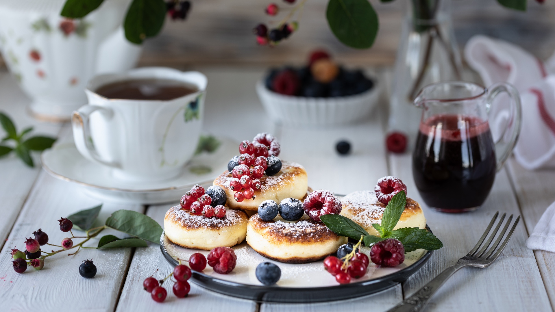 Сырники на столе с ягодами и чаем на завтрак