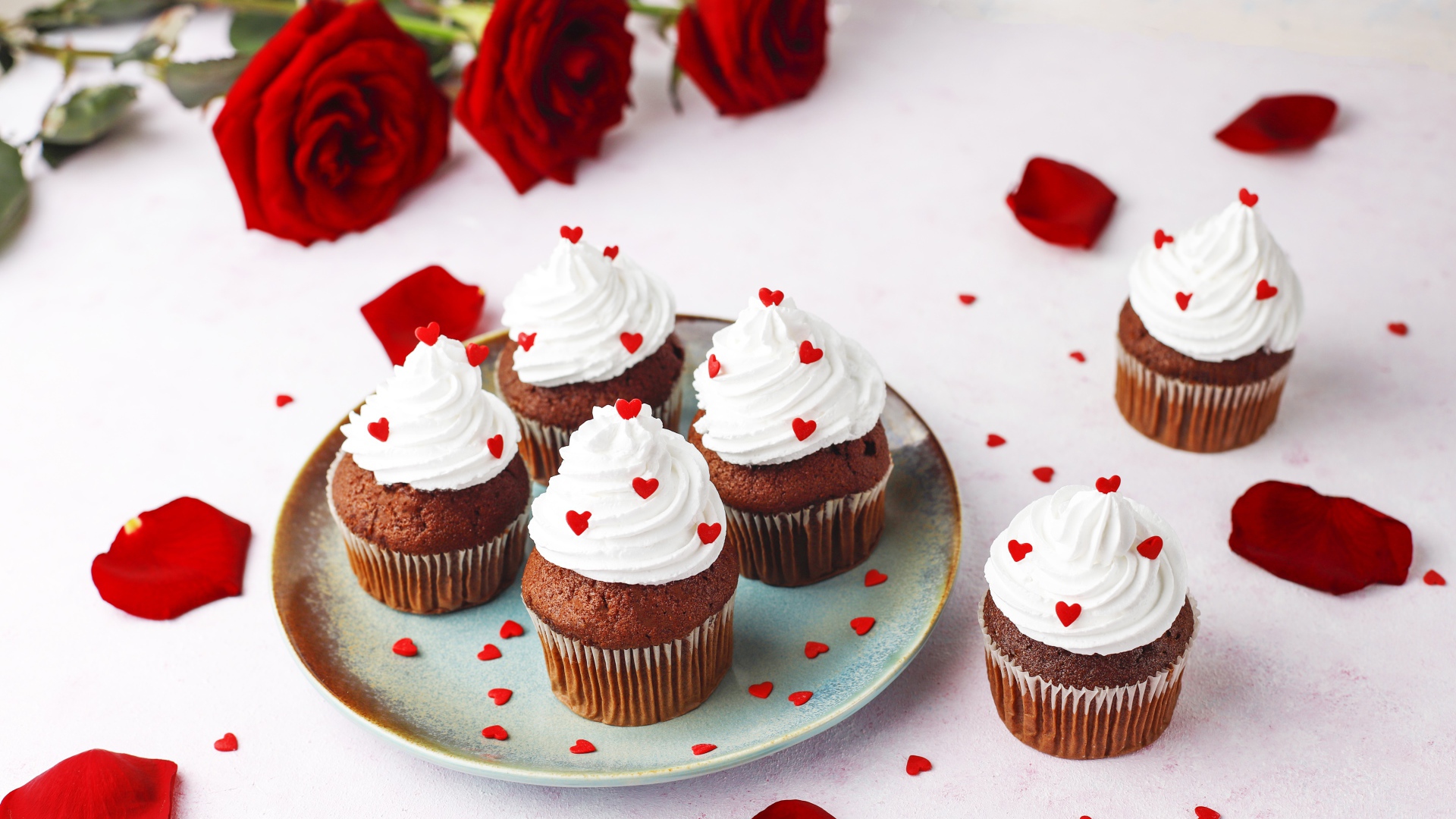 Кексы с кремом на столе с букетом роз 