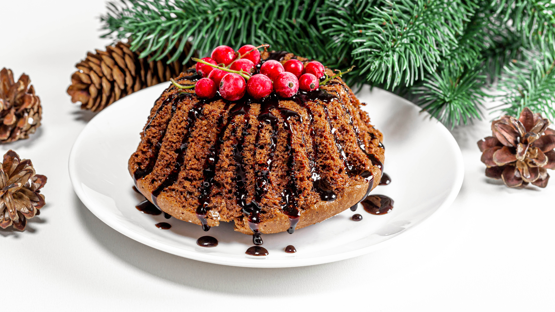 Вкусный кекс с шоколадом и красной смородиной на столе с еловой веткой и шишками