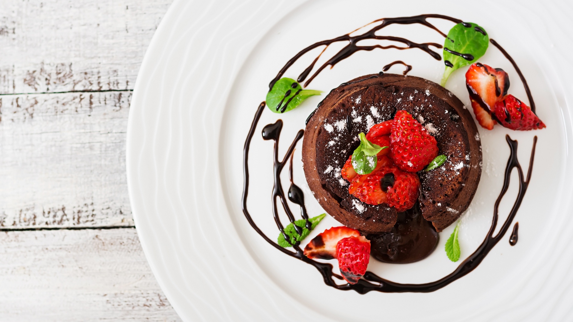 Вкусный десерт на белой тарелке с клубникой и шоколадом