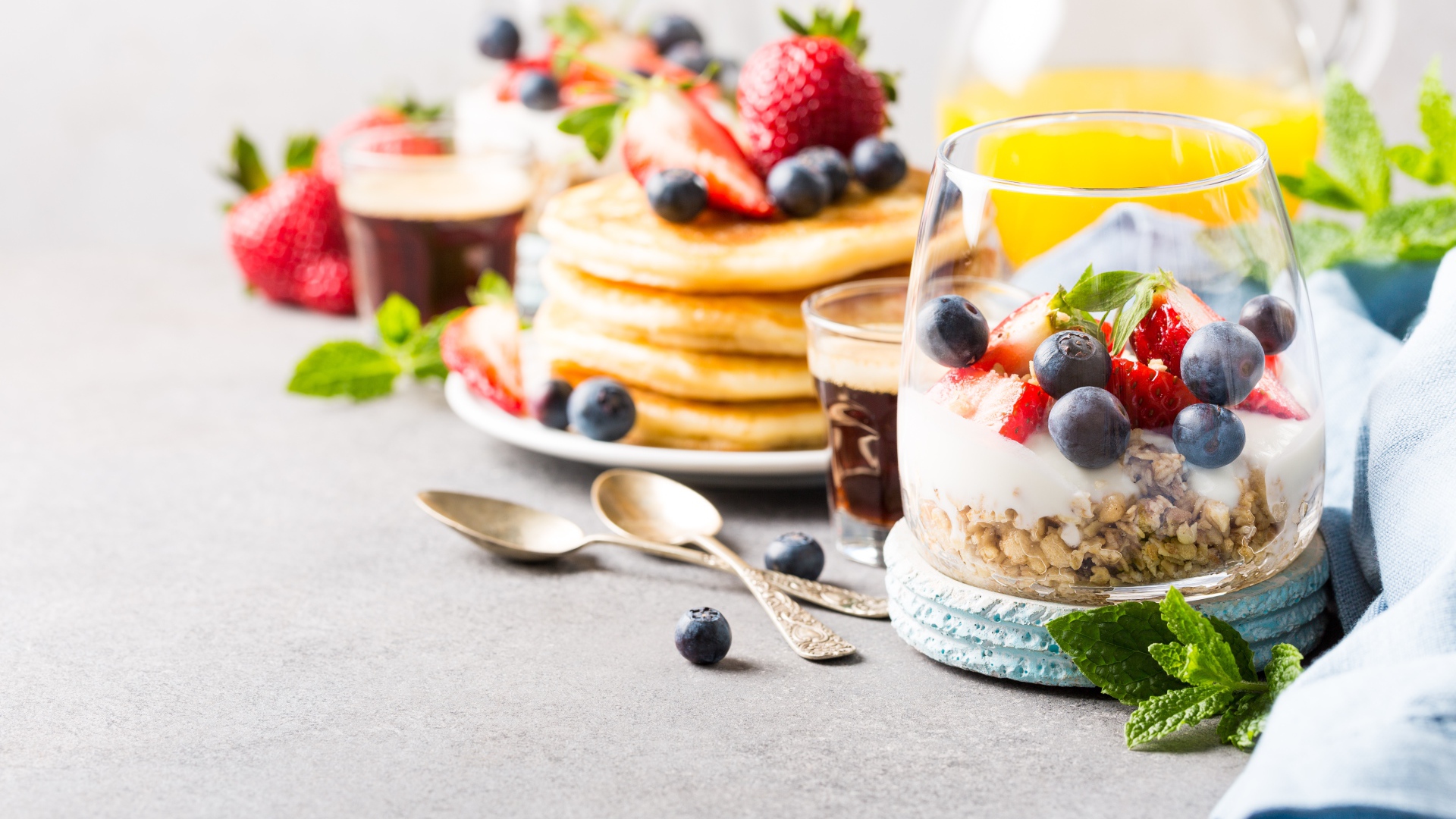 Оладьи на столе с ягодами, мюсли и кофе