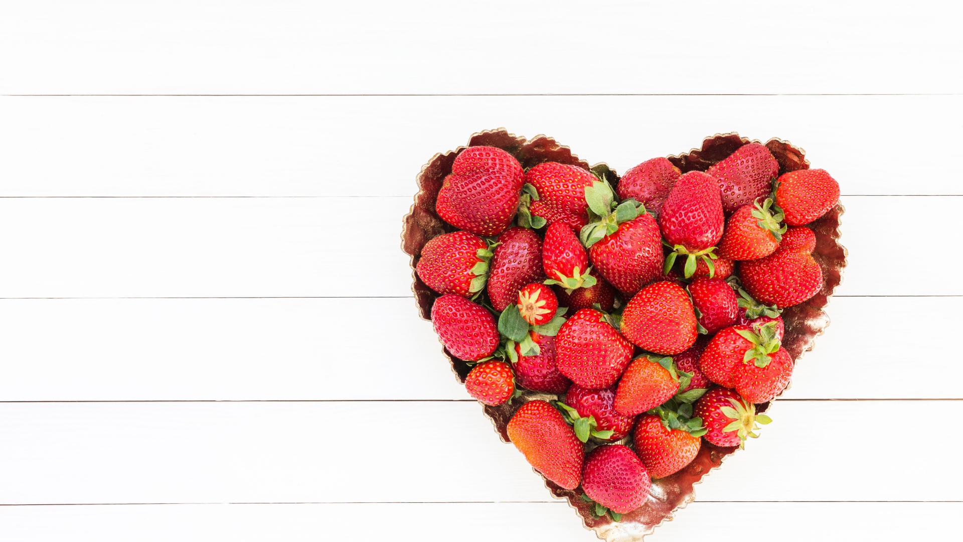 Пирожное в форме сердца с клубникой на белом фоне