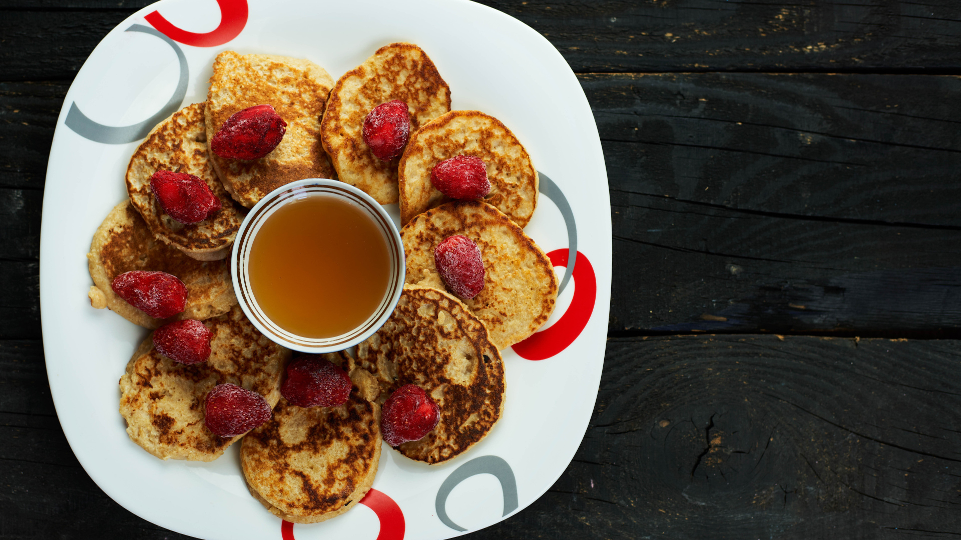 Оладьи на тарелке с клубникой и медом