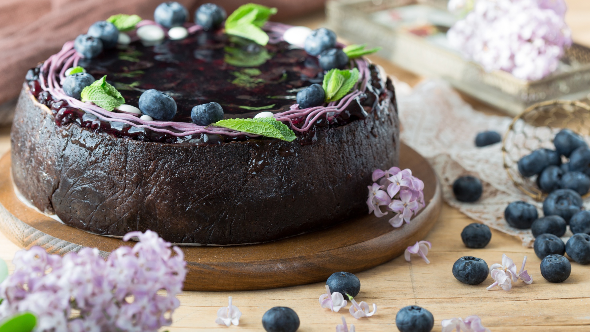 Пирог с джемом и ягодами черники на столе с сиренью 