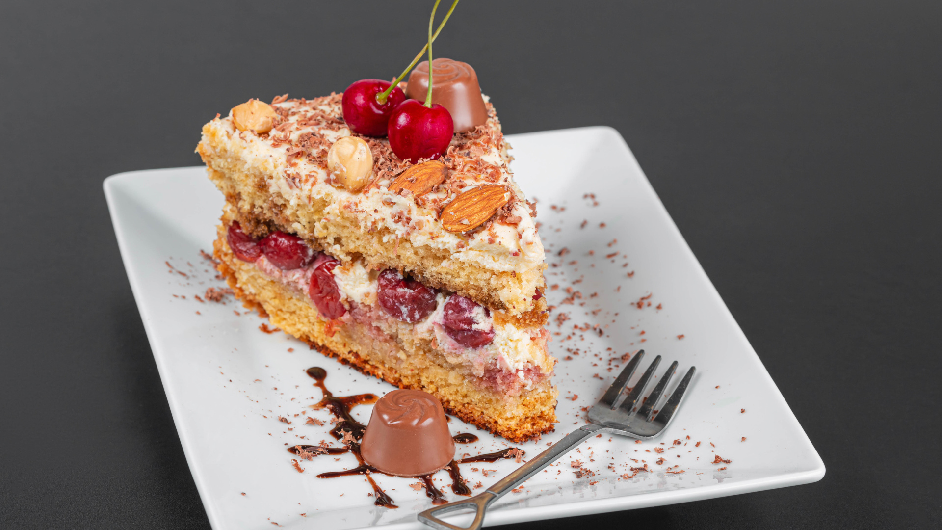 Кусок торта с ягодами вишни и миндальным орехом