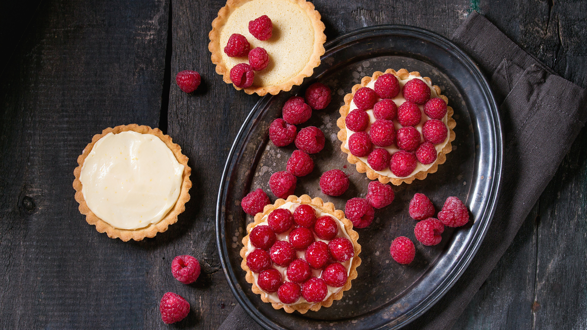 Кексы с кремом на блюде с малиной 